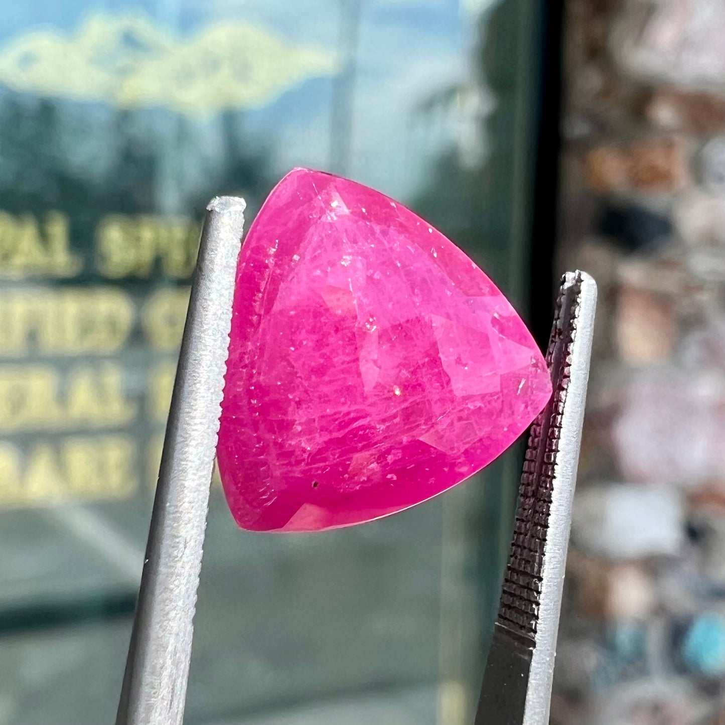 A loose, faceted trillion cut, natural, commercial grade ruby gemstone. The stone is purplish red color.