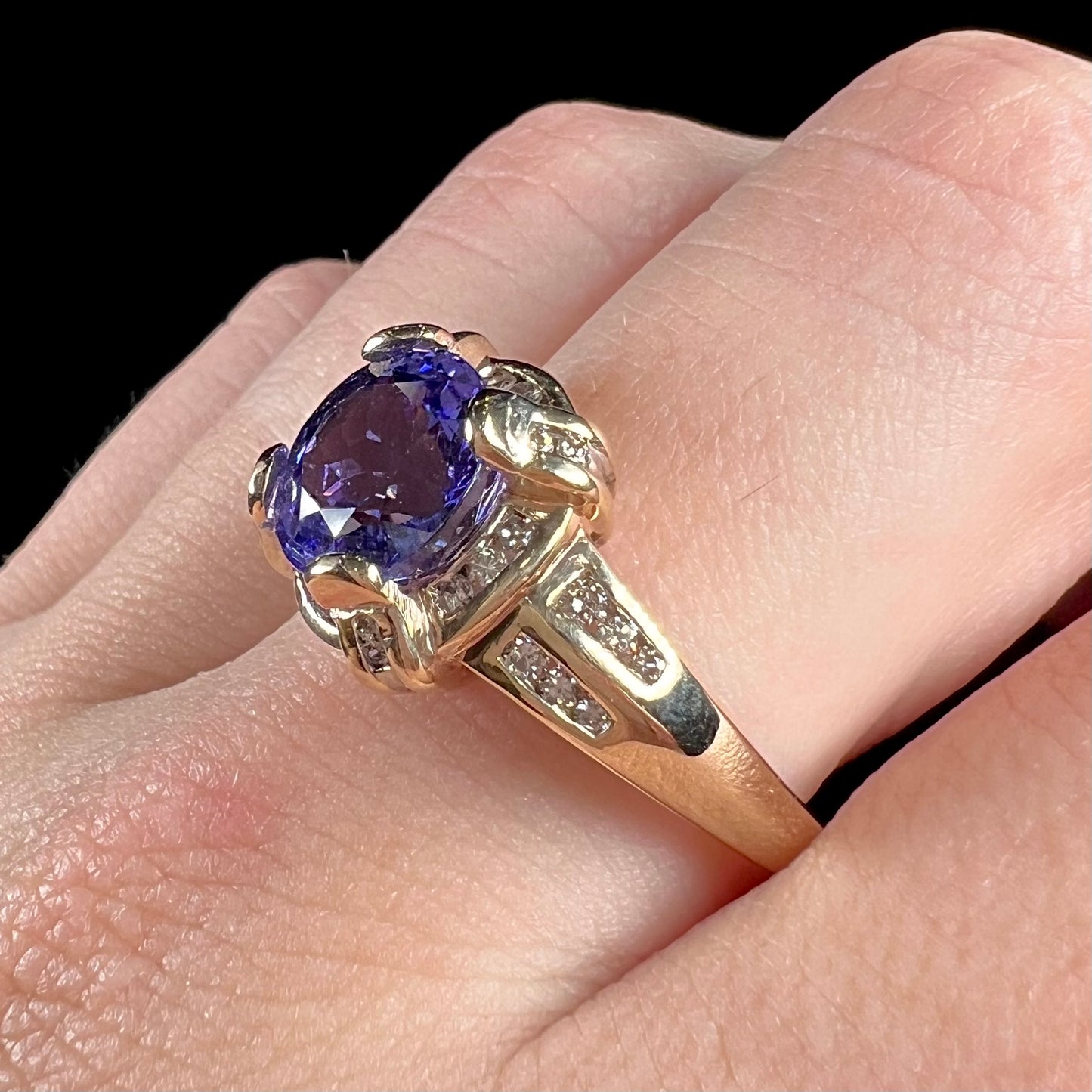 A ladies' yellow gold natural tanzanite and diamond ring. Diamonds are channel set along the shank and in the prongs.