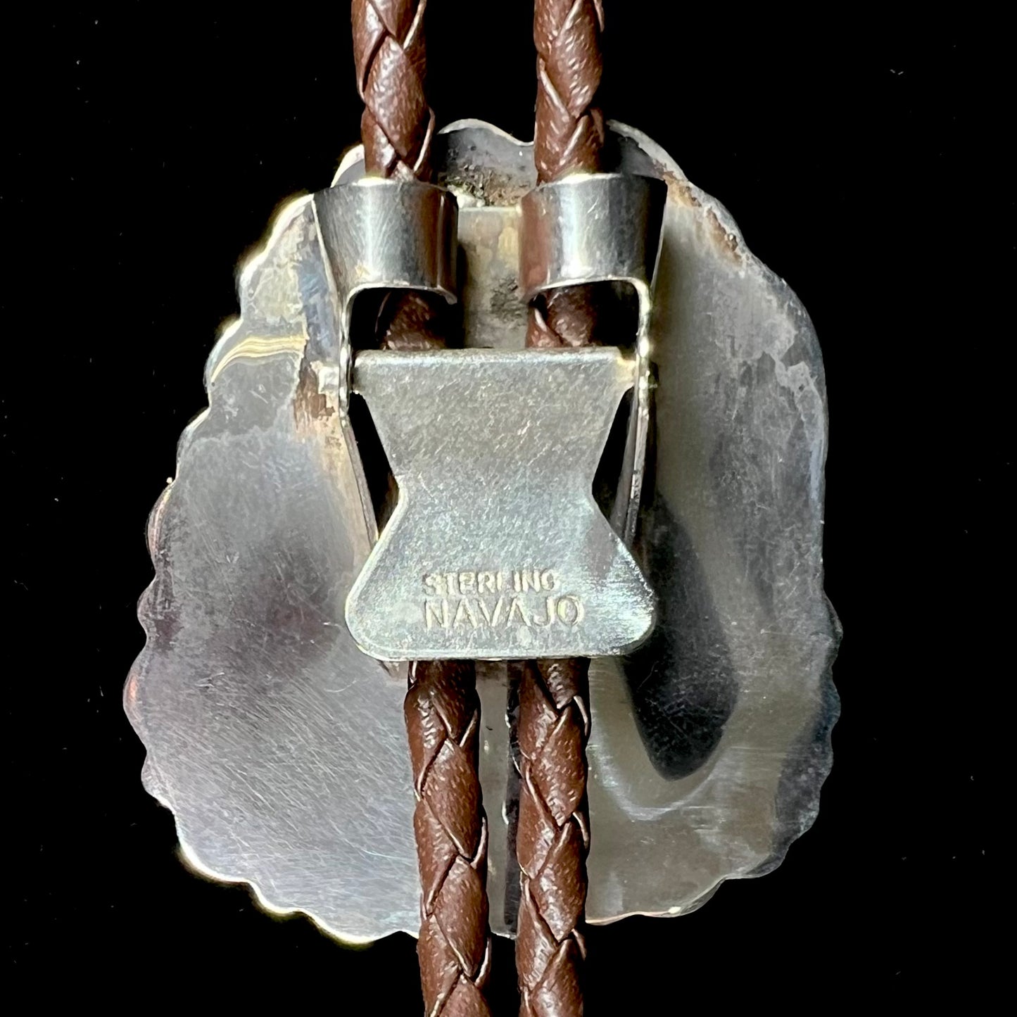 A men's sterling silver, Navajo style bolo tie set with a Pilot Mountain turquoise stone. The rope is brown leather.