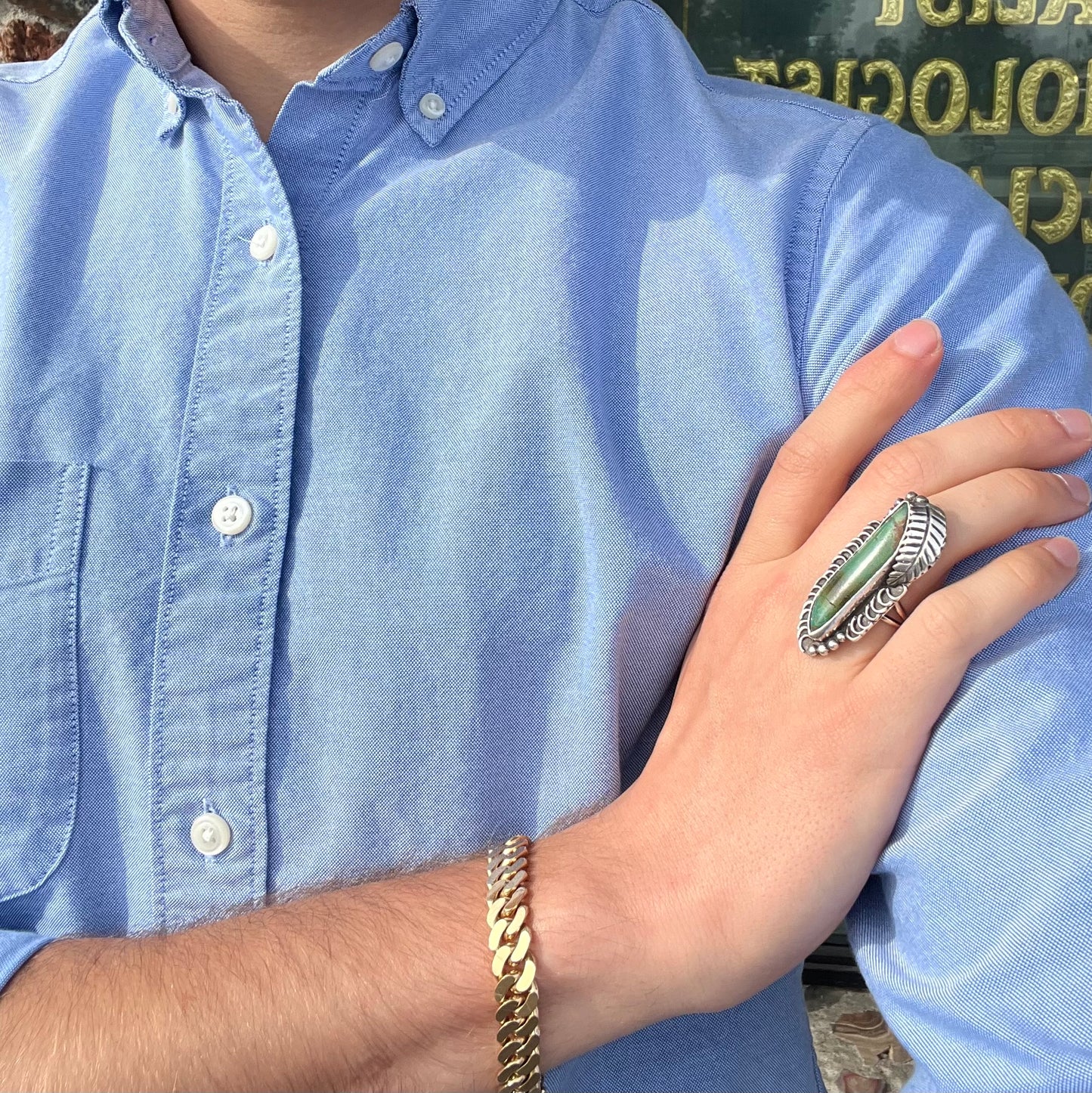 A sterling silver Navajo style ring set with a turquoise stone that shows colors of green, yellow, and reddish brown.