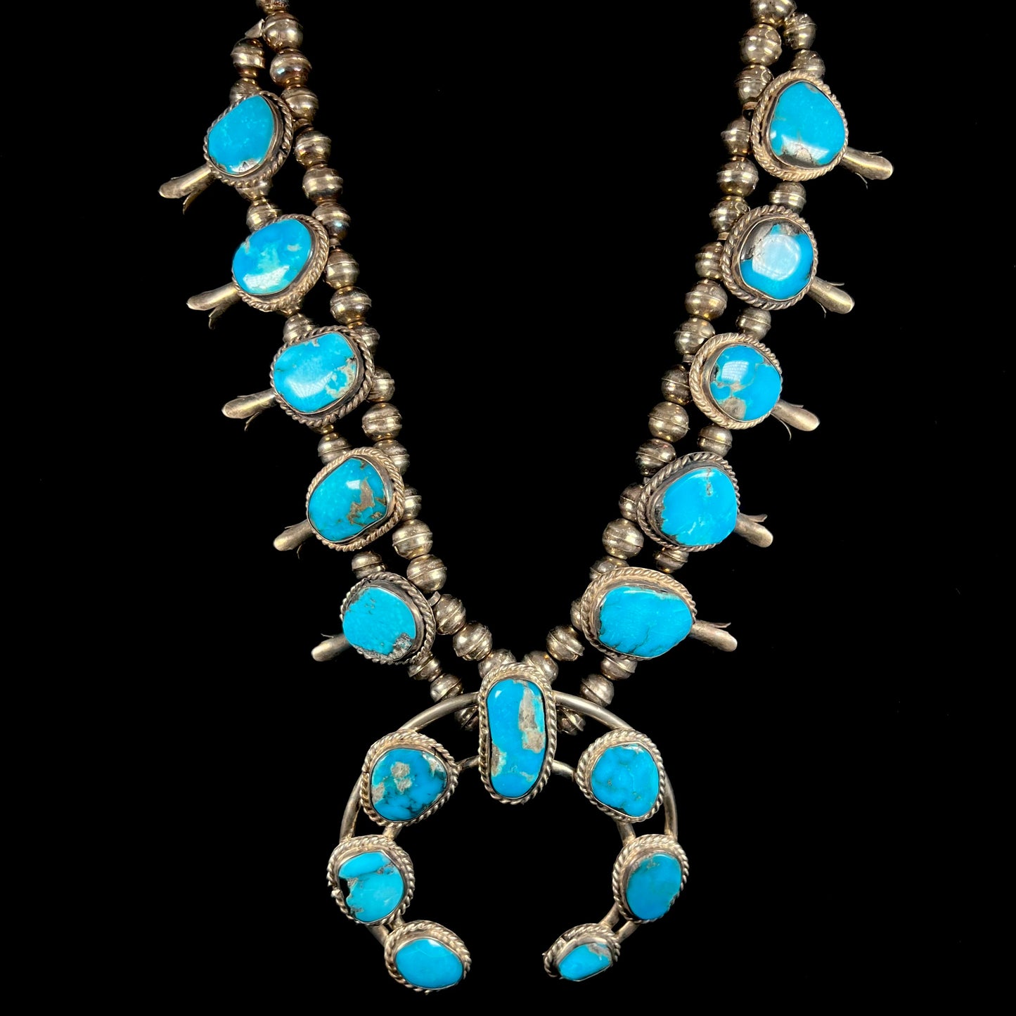 A vintage Navajo squash blossom necklace set with blue Kingman turquoise stones.