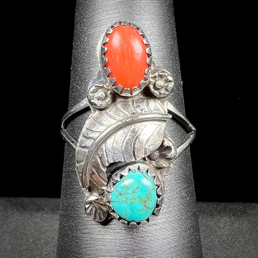 A vintage sterling silver Navajo style ring set with turquoise and coral stones and a feather design.