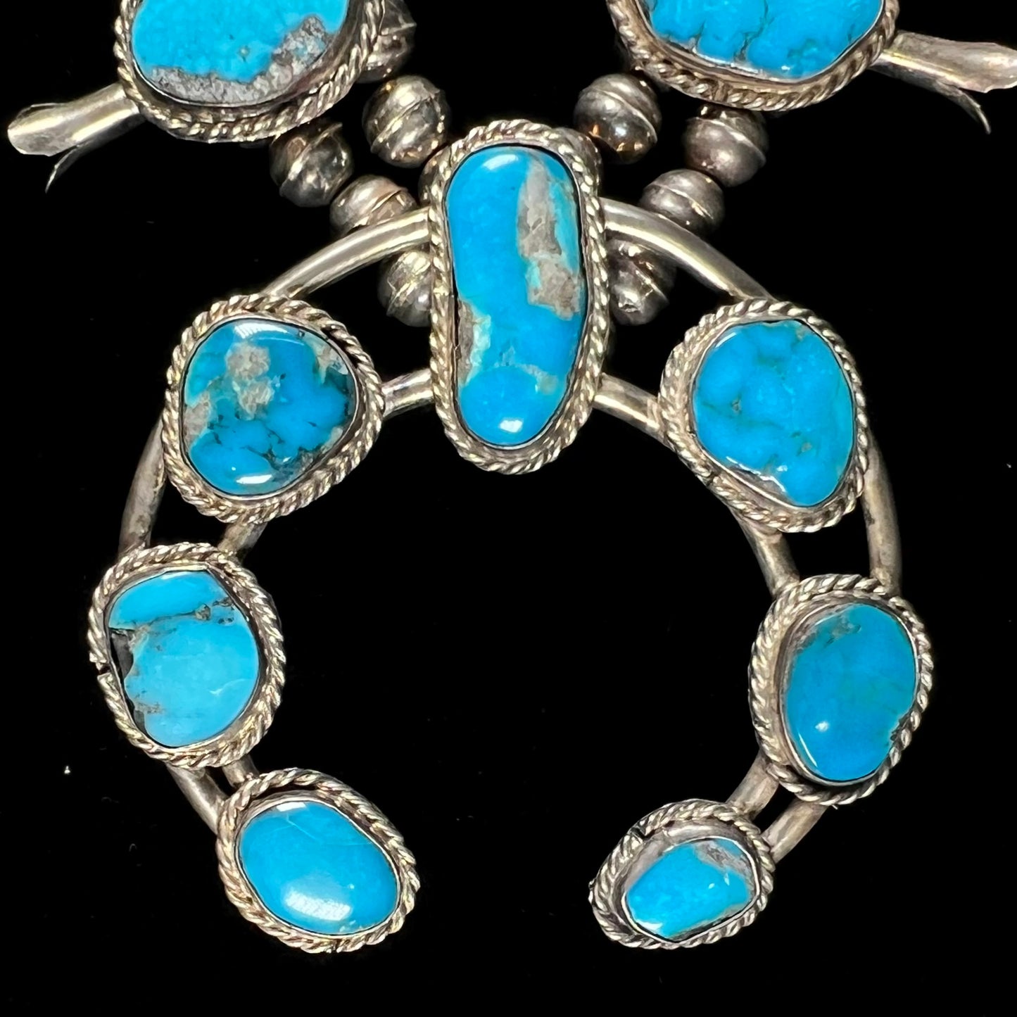 A vintage Navajo squash blossom necklace set with blue Kingman turquoise stones.