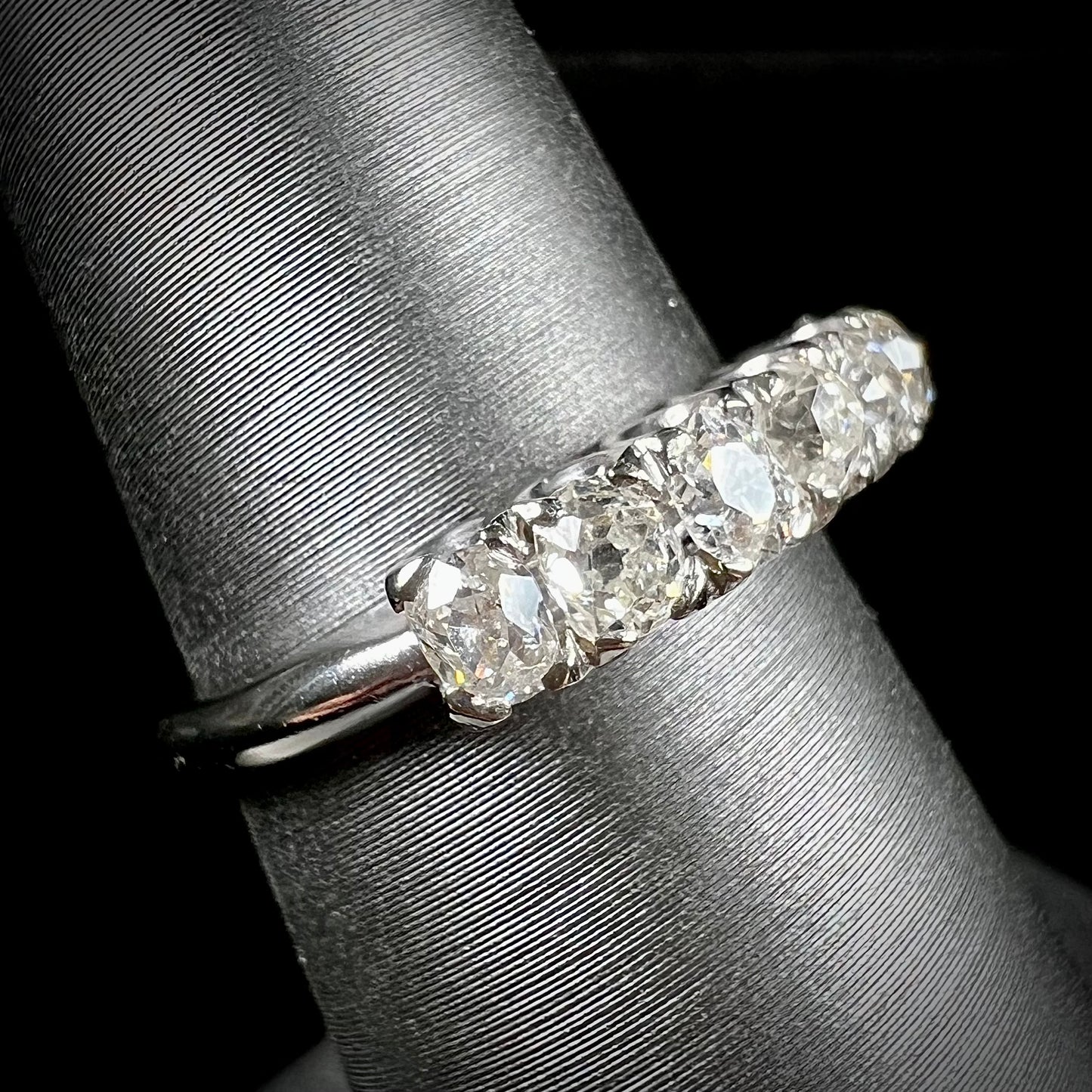 An antique white gold diamond wedding band set with six old mine cut natural diamonds.