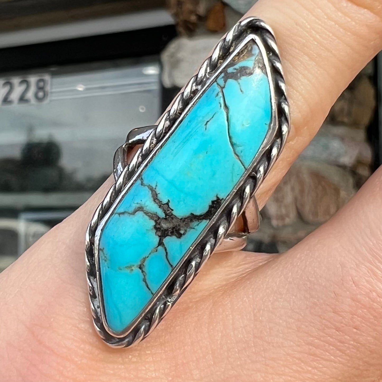 A vintage, Southwest style sterling silver ring set with a natural turquoise stone. The stone is blue with a black matrix.