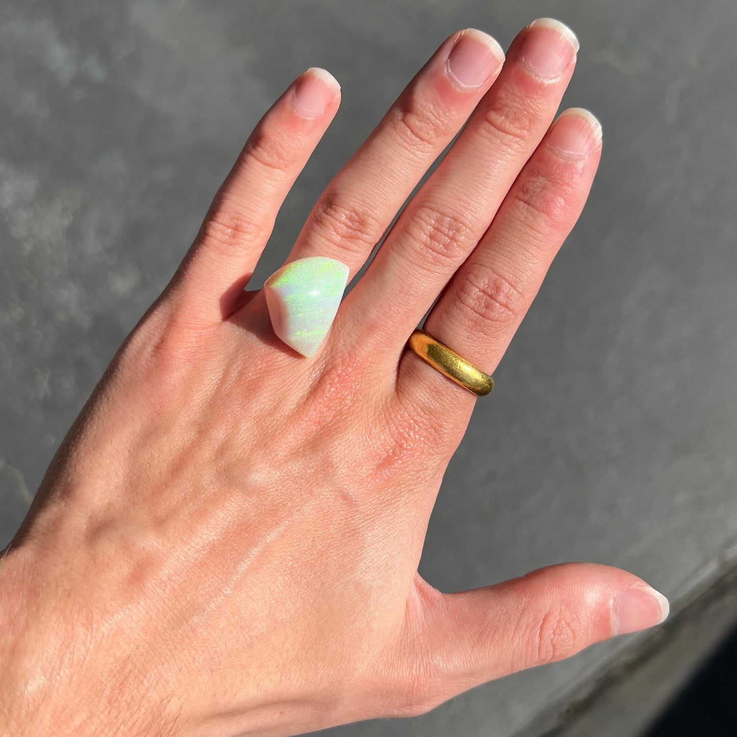 A polished double-sided opal specimen from Andamooka, Australia. The opal has green, orange, and blue colors.