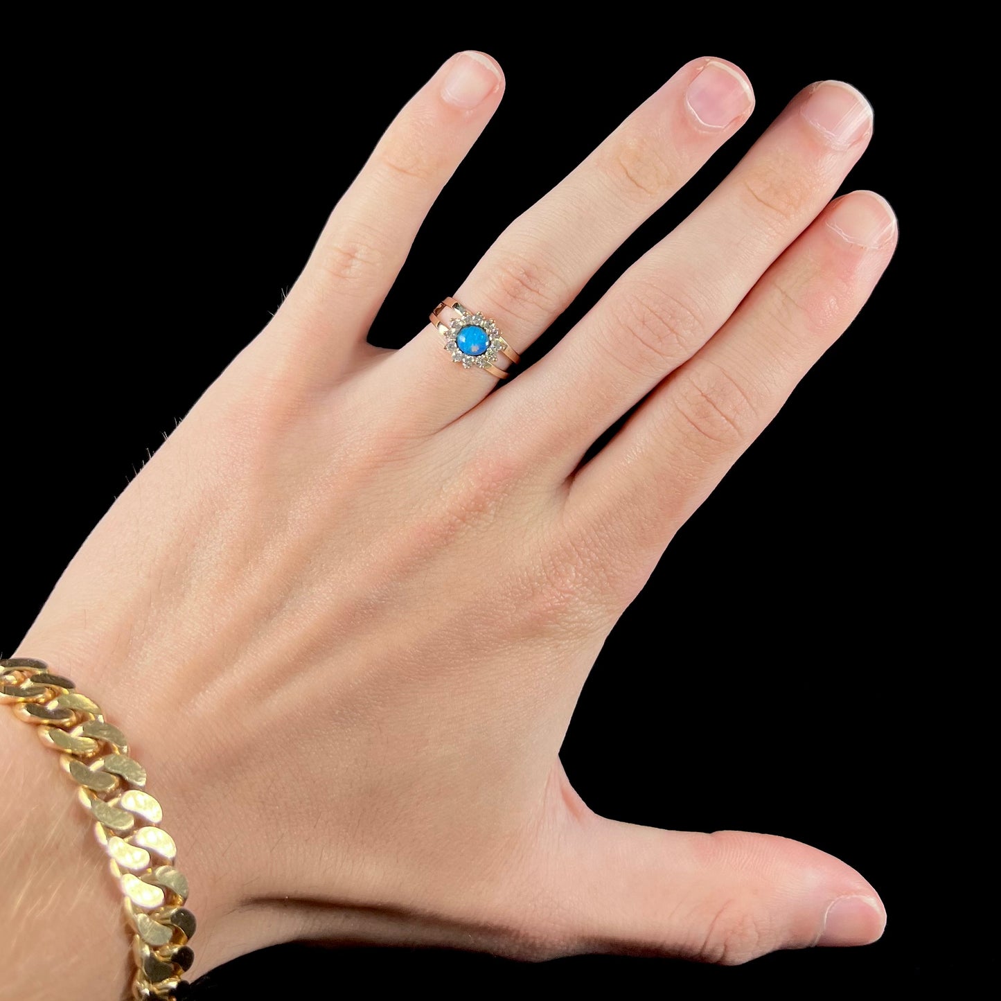 A ladies' round cut black opal and diamond halo ring. The ring is yellow gold and has a split shank.