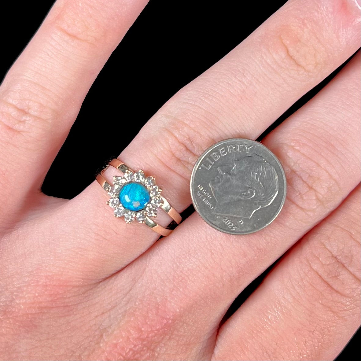 A ladies' round cut black opal and diamond halo ring. The ring is yellow gold and has a split shank.