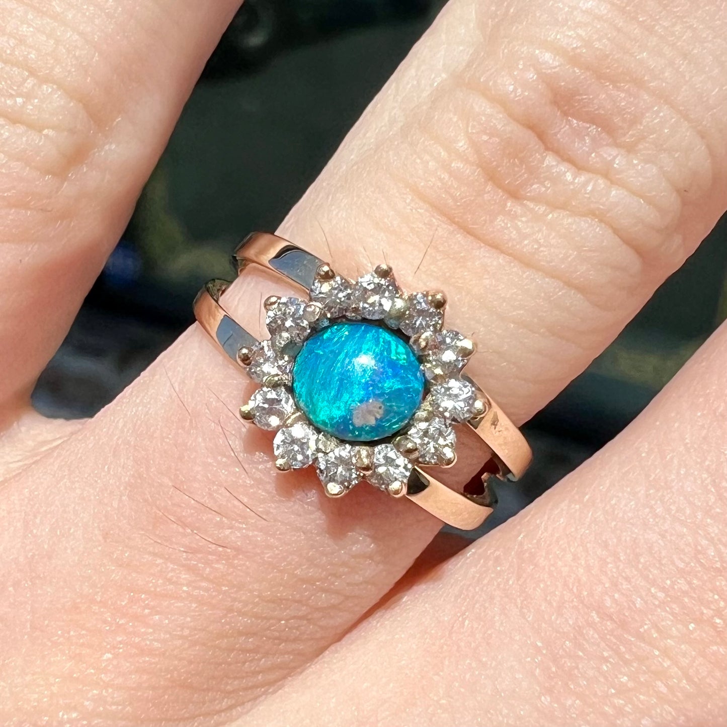 A ladies' round cut black opal and diamond halo ring. The ring is yellow gold and has a split shank.