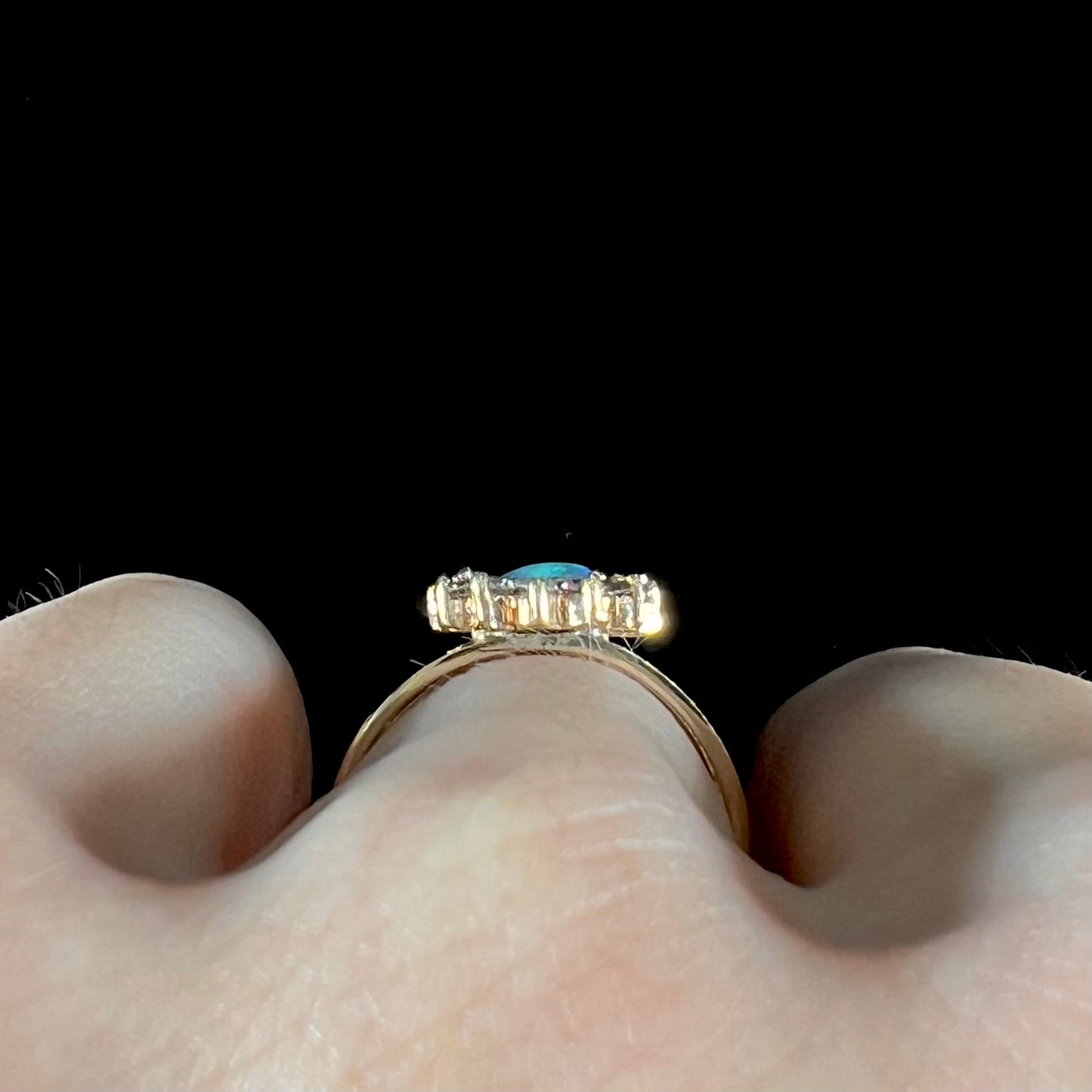 A ladies' round cut black opal and diamond halo ring. The ring is yellow gold and has a split shank.