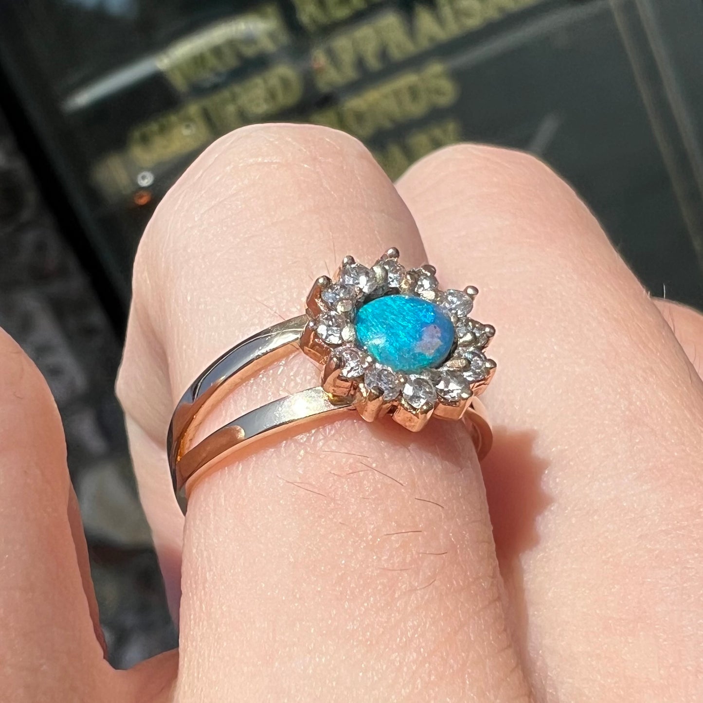 A ladies' round cut black opal and diamond halo ring. The ring is yellow gold and has a split shank.