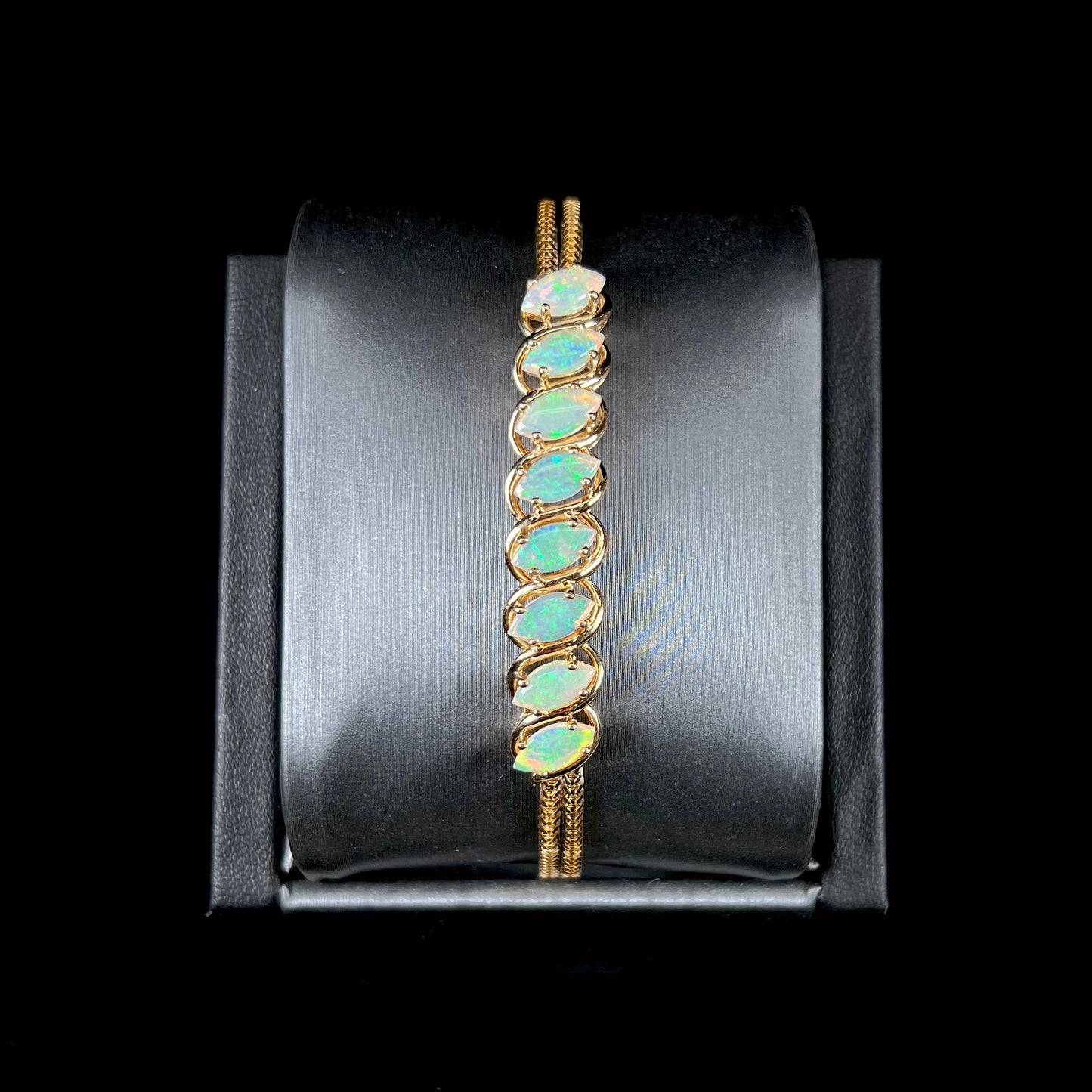 A ladies' yellow gold bracelet prong set with eight natural, marquise cabochon cut opals.