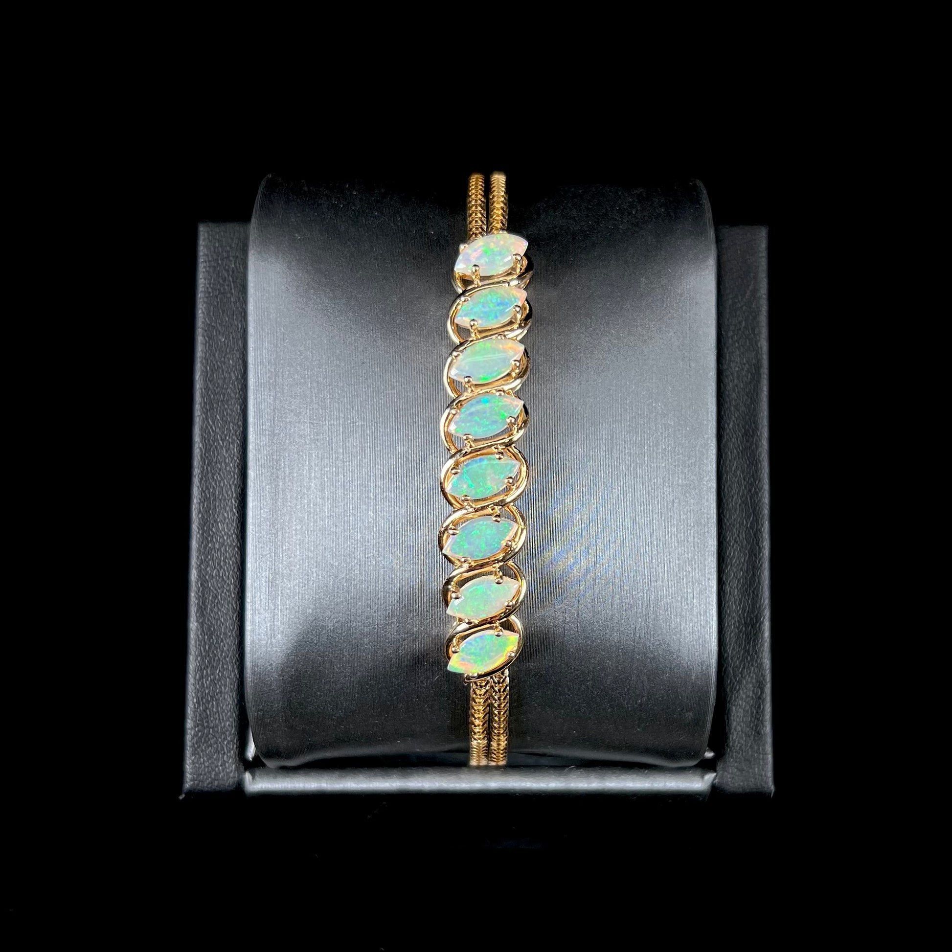 A ladies' yellow gold bracelet prong set with eight natural, marquise cabochon cut opals.