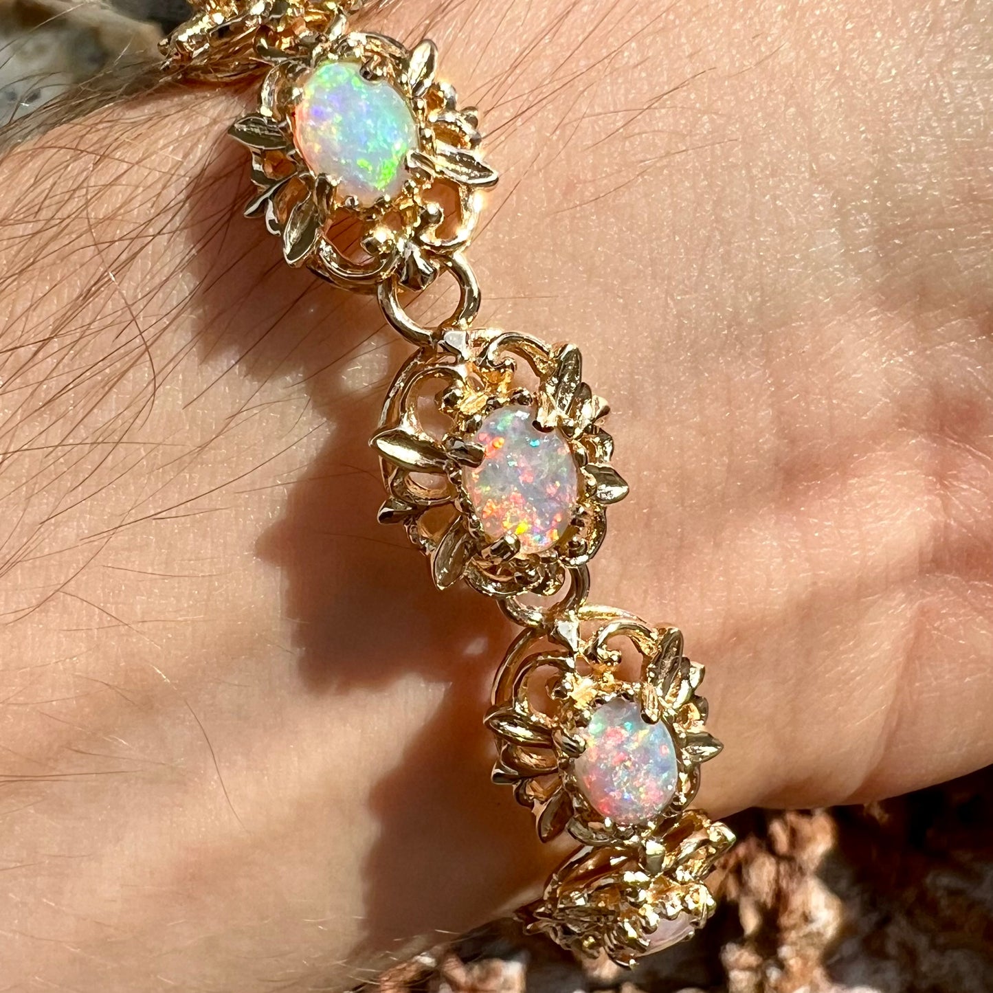 A ladies' yellow gold bracelet set with natural, oval cabochon cut white crystal opals.