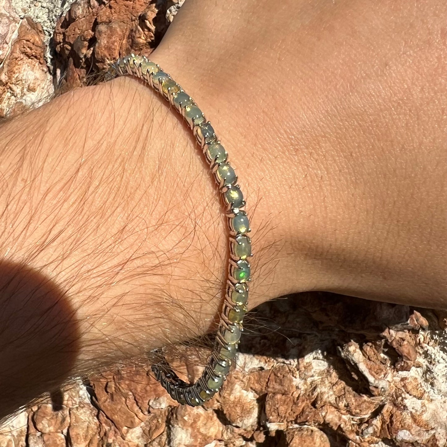 A ladies' sterling silver tennis style bracelet set with natural orange yellow Mexican fire opals.