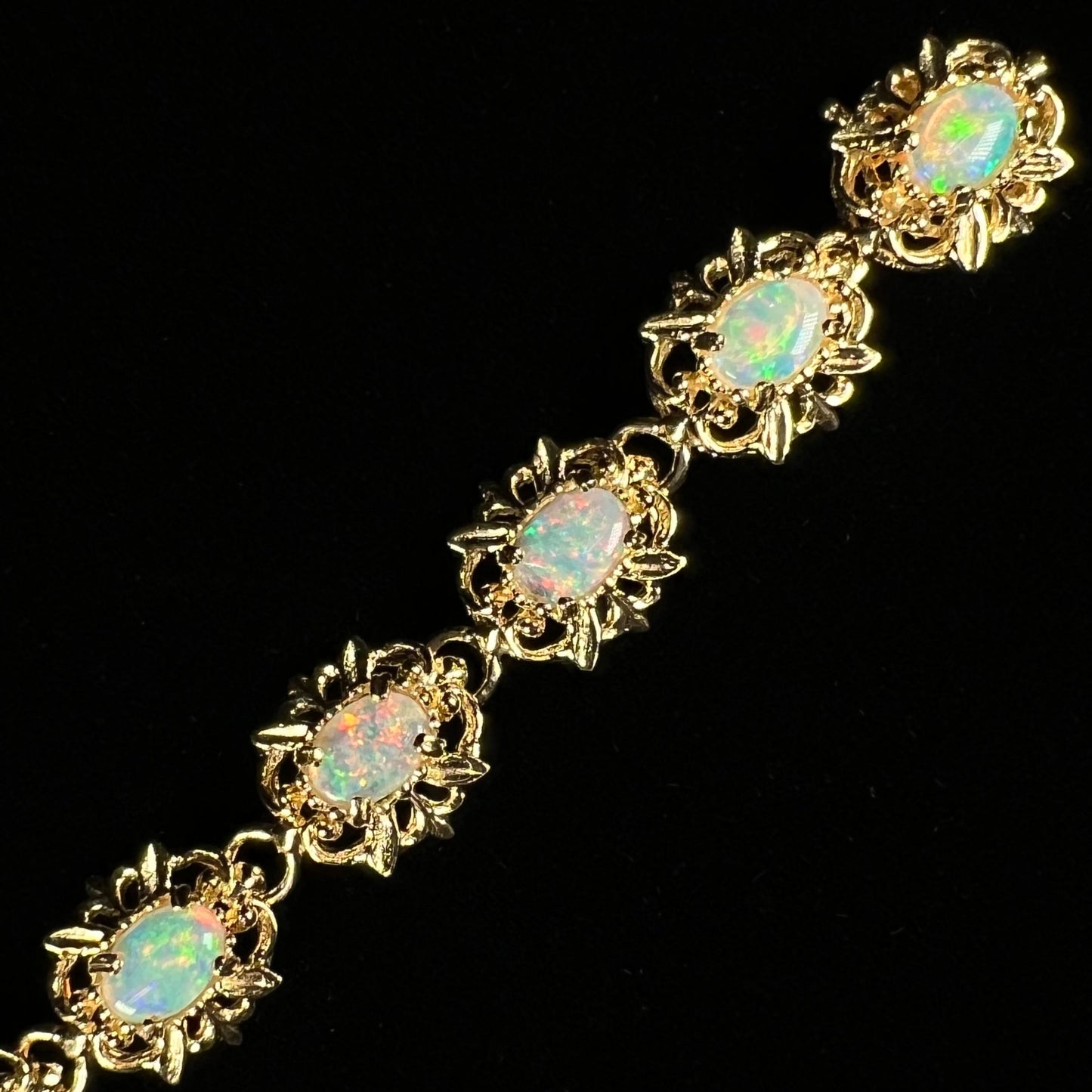 A ladies' yellow gold bracelet set with natural, oval cabochon cut white crystal opals.