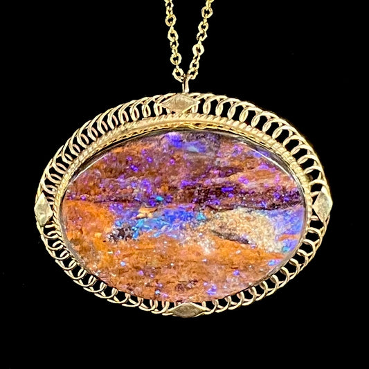 A yellow gold filigree style brooch/pendant combination piece set with a purple opalized wood stone from Duck Creek, Australia.