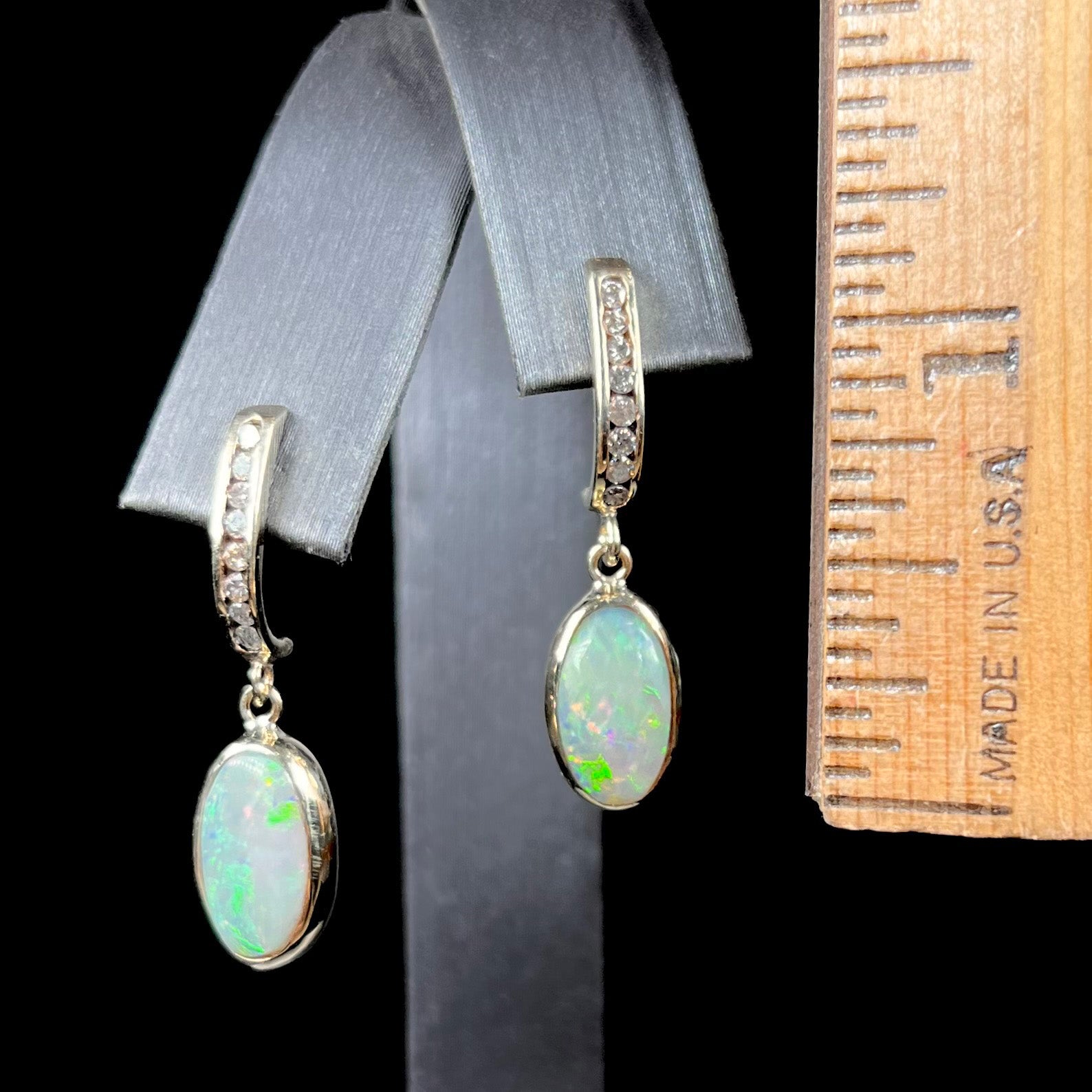 A pari of yellow gold dangle earrings set with natural white crystal opals and diamond accents.