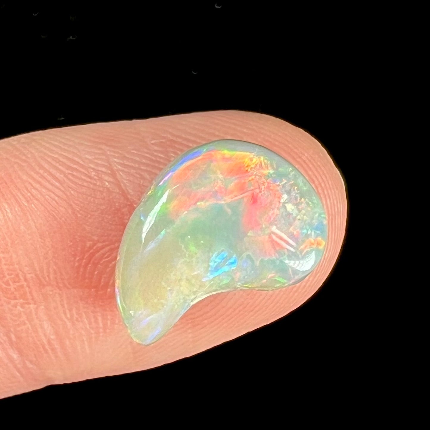 A loose, drop shaped opal stone from Lightning Ridge, Australia. The stone has bright red fire.