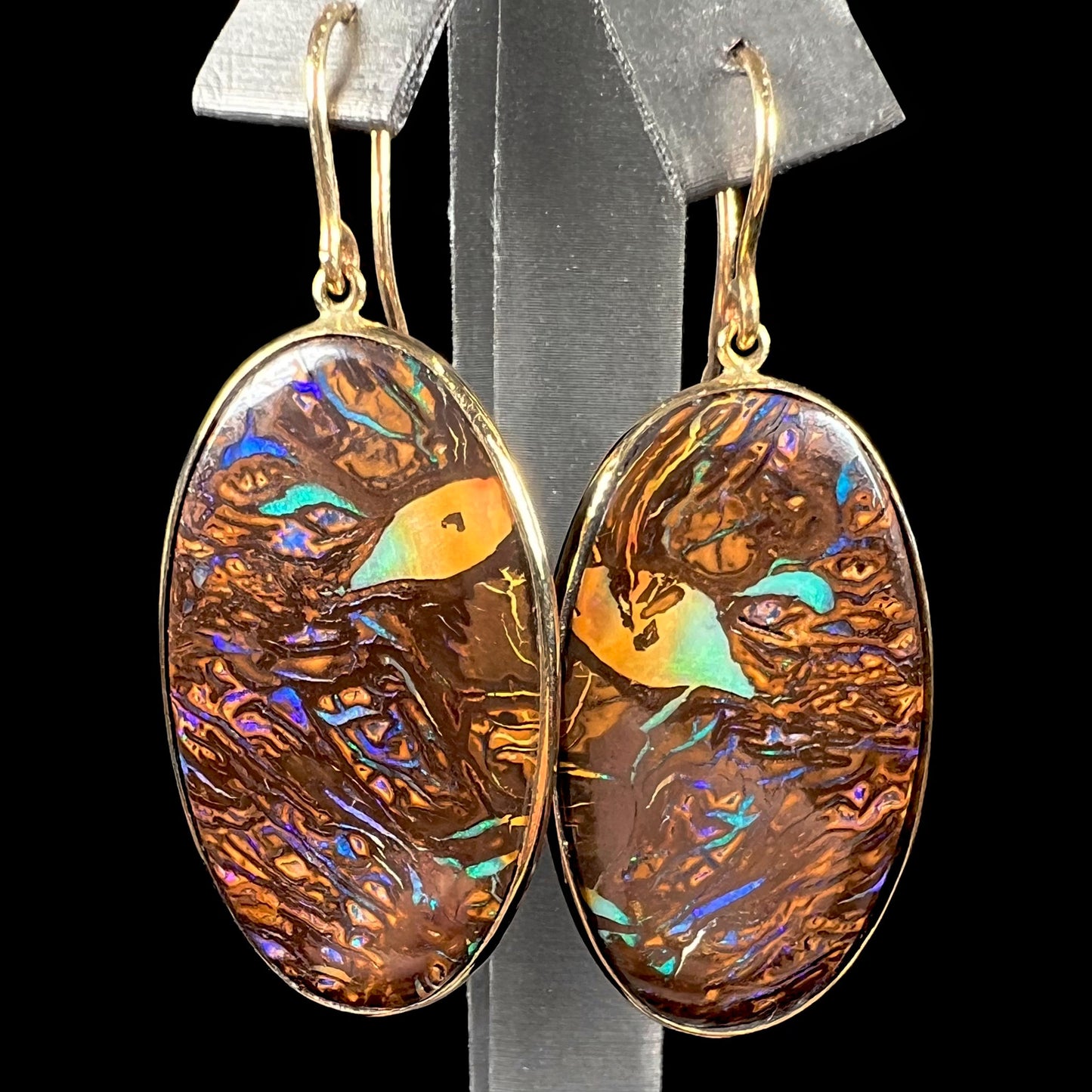 A pair of Koroit boulder opal dangle earrings set in yellow gold bezels.