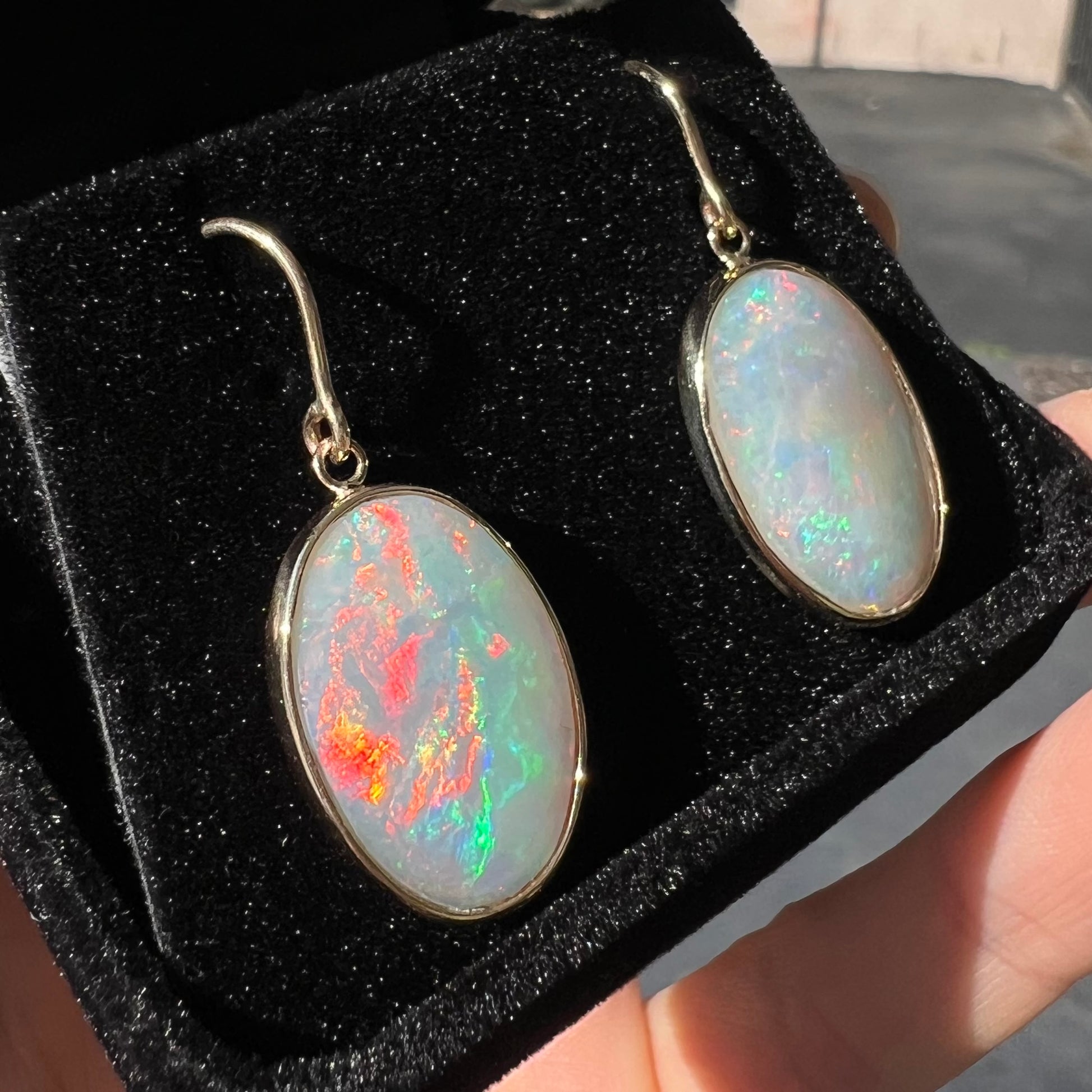 A pair of yellow gold earrings bezel set with oval cabochon cut natural opal stones.