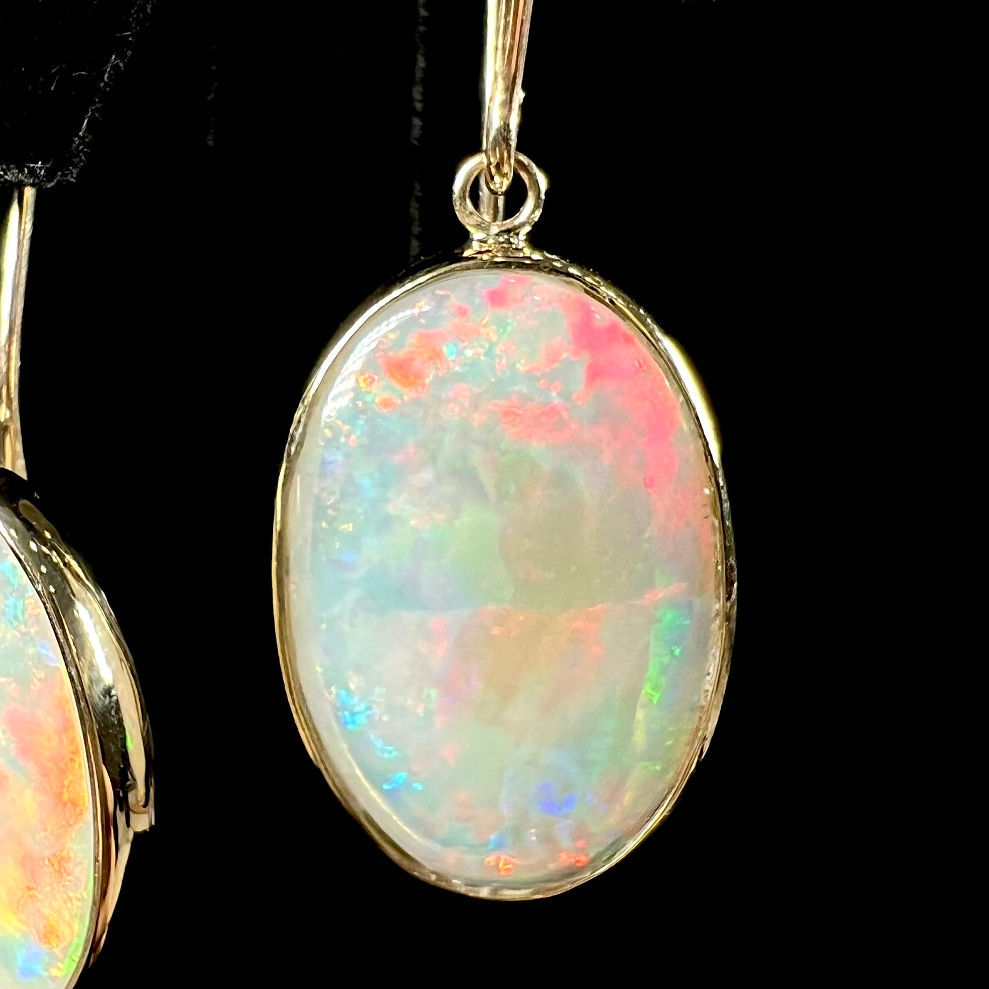 A pair of yellow gold earrings bezel set with oval cabochon cut natural opal stones.