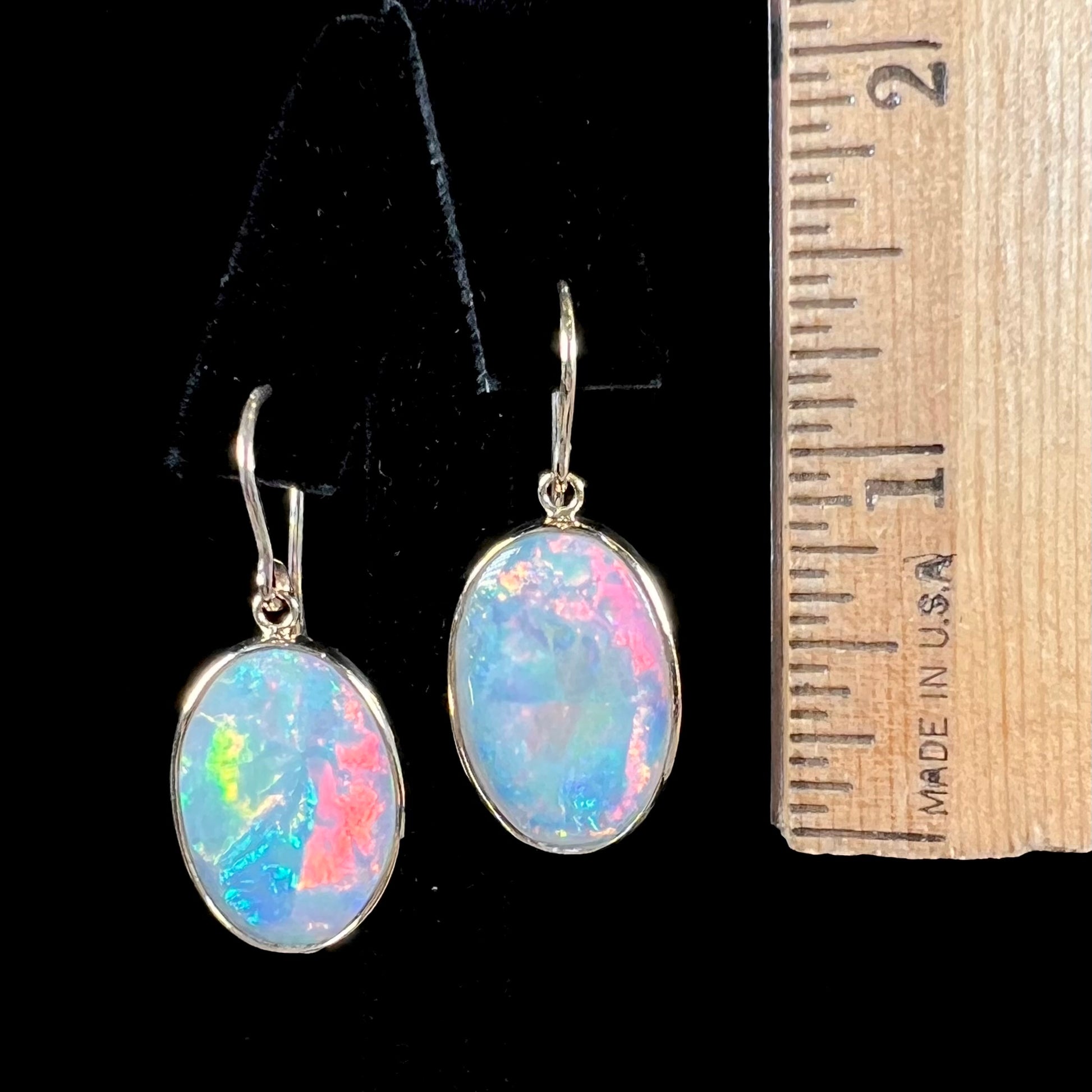 A pair of yellow gold earrings bezel set with oval cabochon cut natural opal stones.