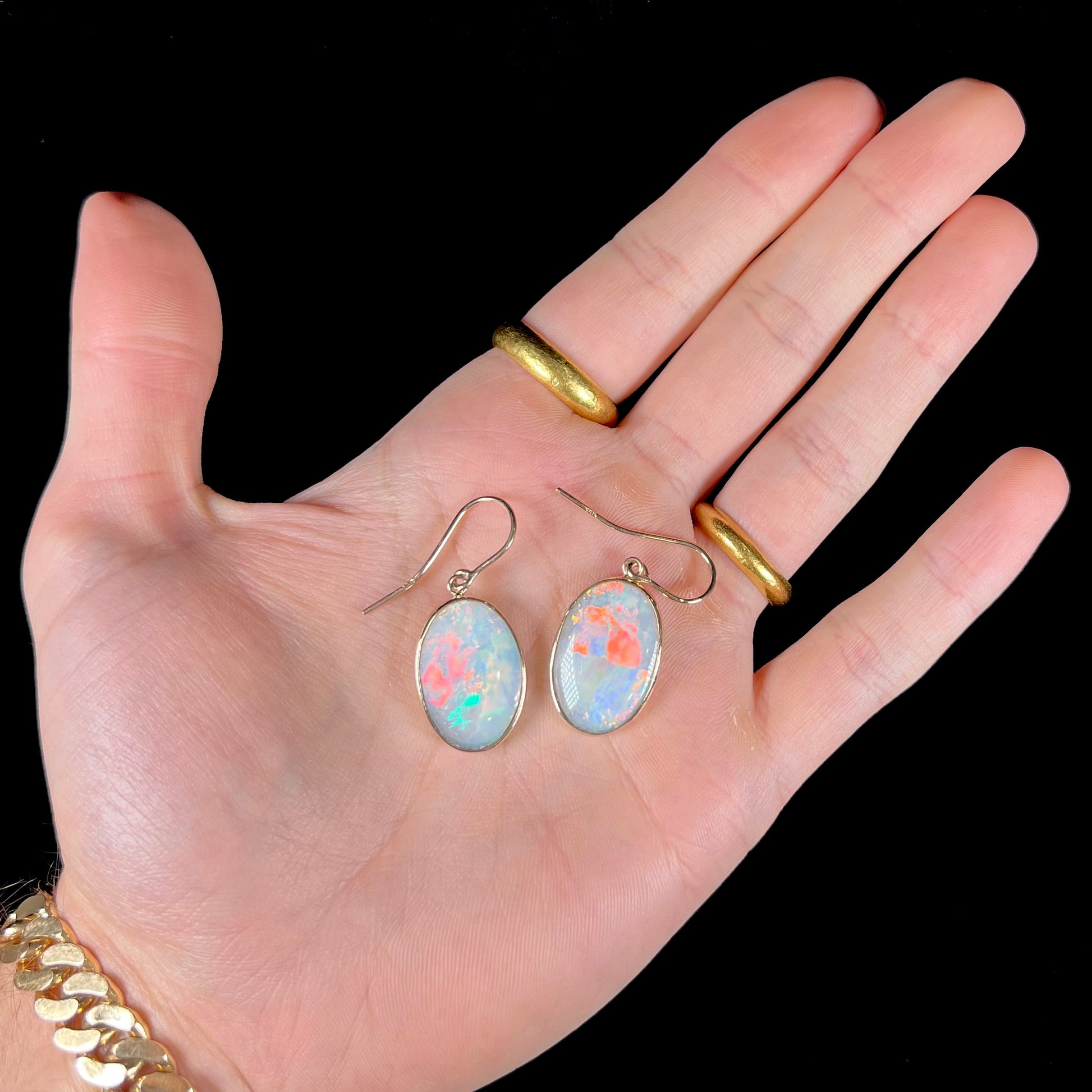 A pair of yellow gold earrings bezel set with oval cabochon cut natural opal stones.