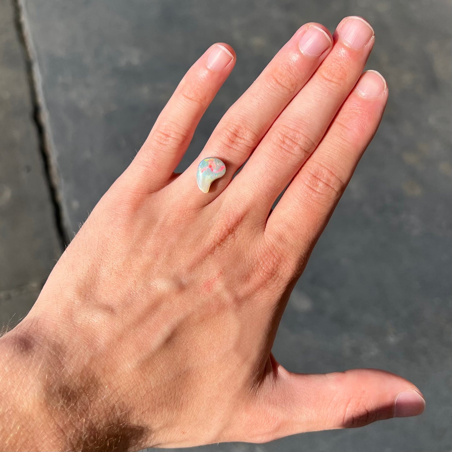 A loose, drop shaped opal stone from Lightning Ridge, Australia. The stone has bright red fire.