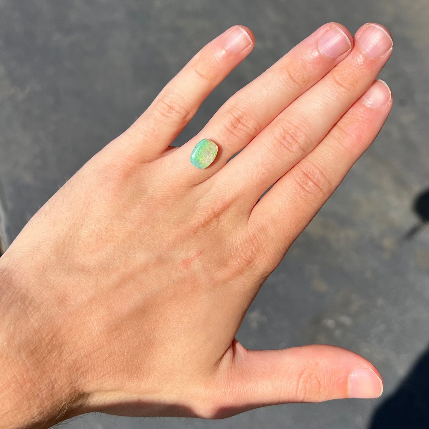 A 2.40ct barrel shaped Lightning Ridge semi-crystal opal. The stone has blue and green colors.