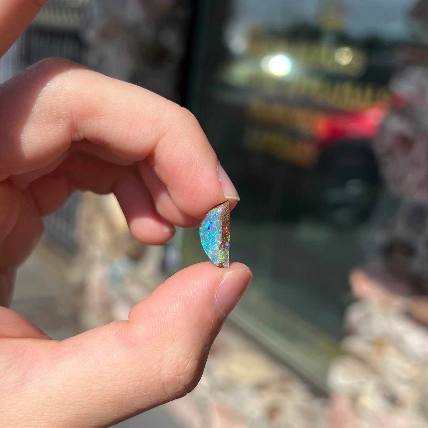 A freeform shaped boulder opal stone from Quilpie, Australia. The opal has bright blue and green play of color.