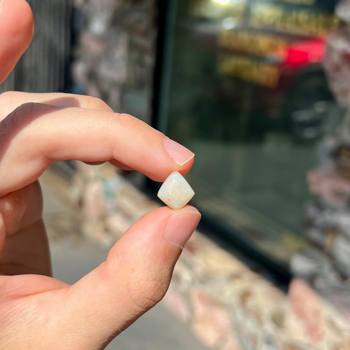 A loose, kite shaped white opal stone from Coober Pedy, Australia. The stone has subdued red colors.