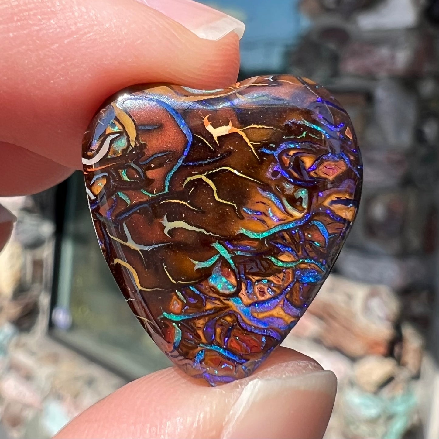 A heart shaped boulder opal stone with purple veins.