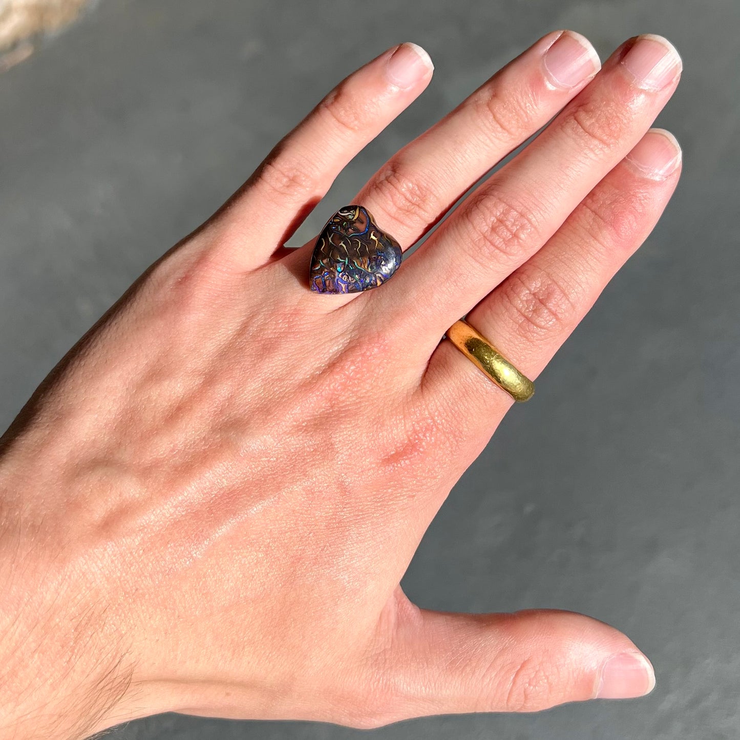 A heart shaped boulder opal stone with purple veins.