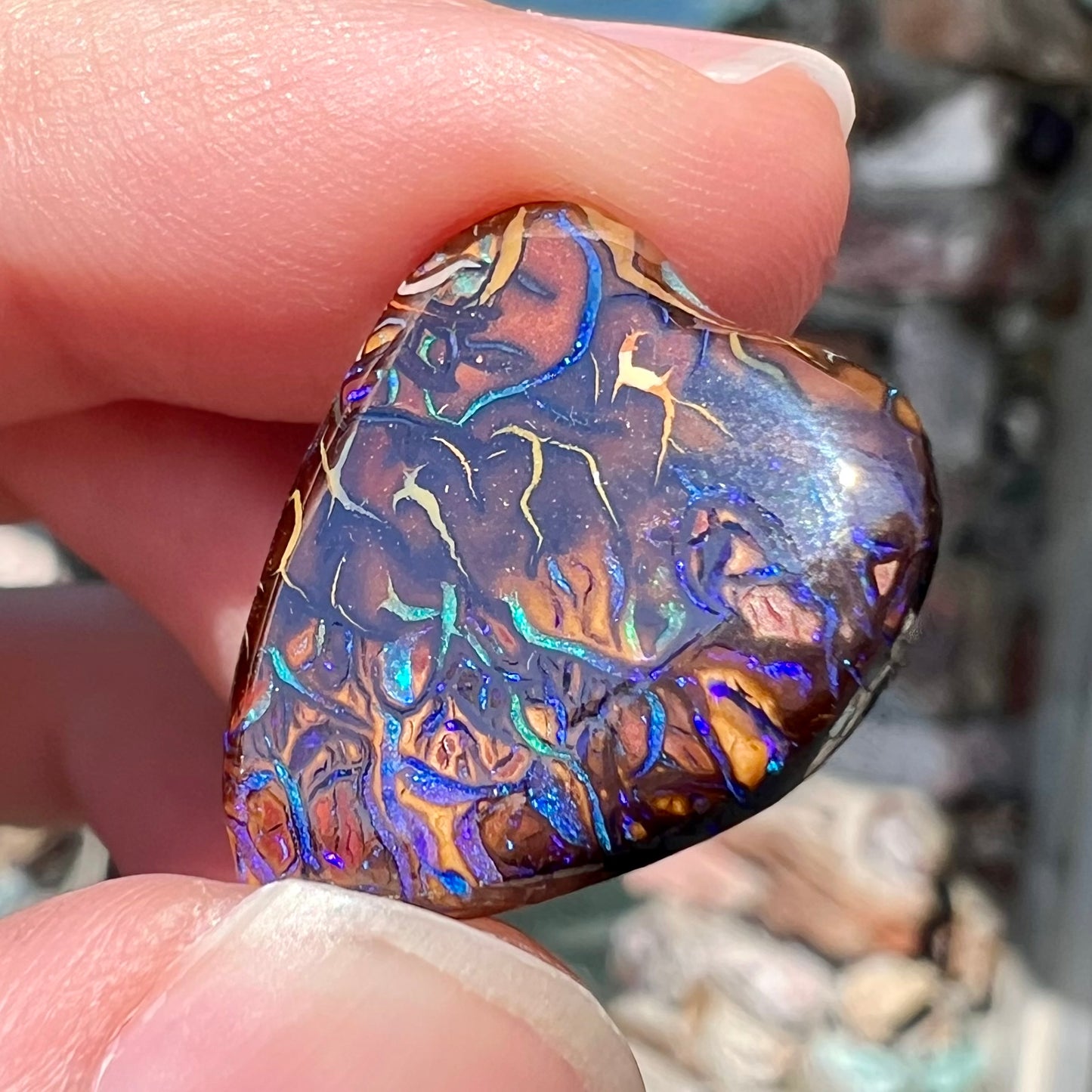 A heart shaped boulder opal stone with purple veins.