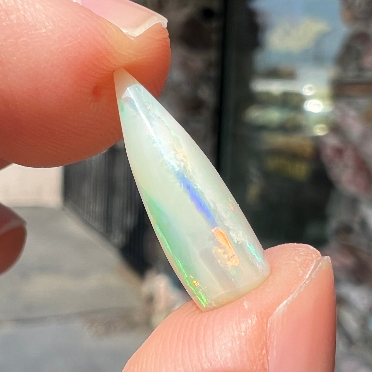 An opalized belemnite fossil from Coober Pedy, Australia. The specimen has red, yellow, and green play of color.