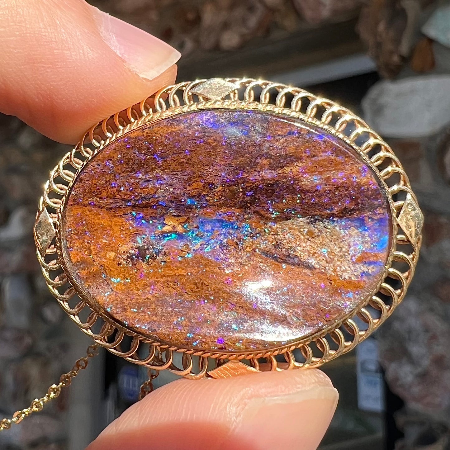 A yellow gold filigree style brooch/pendant combination piece set with a purple opalized wood stone from Duck Creek, Australia.