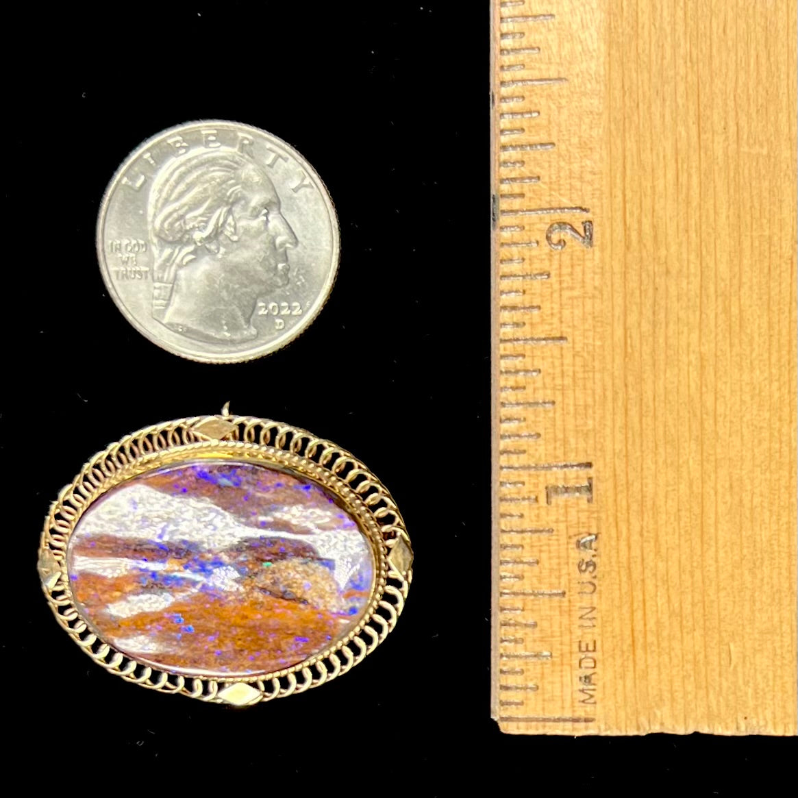 A yellow gold filigree style brooch/pendant combination piece set with a purple opalized wood stone from Duck Creek, Australia.