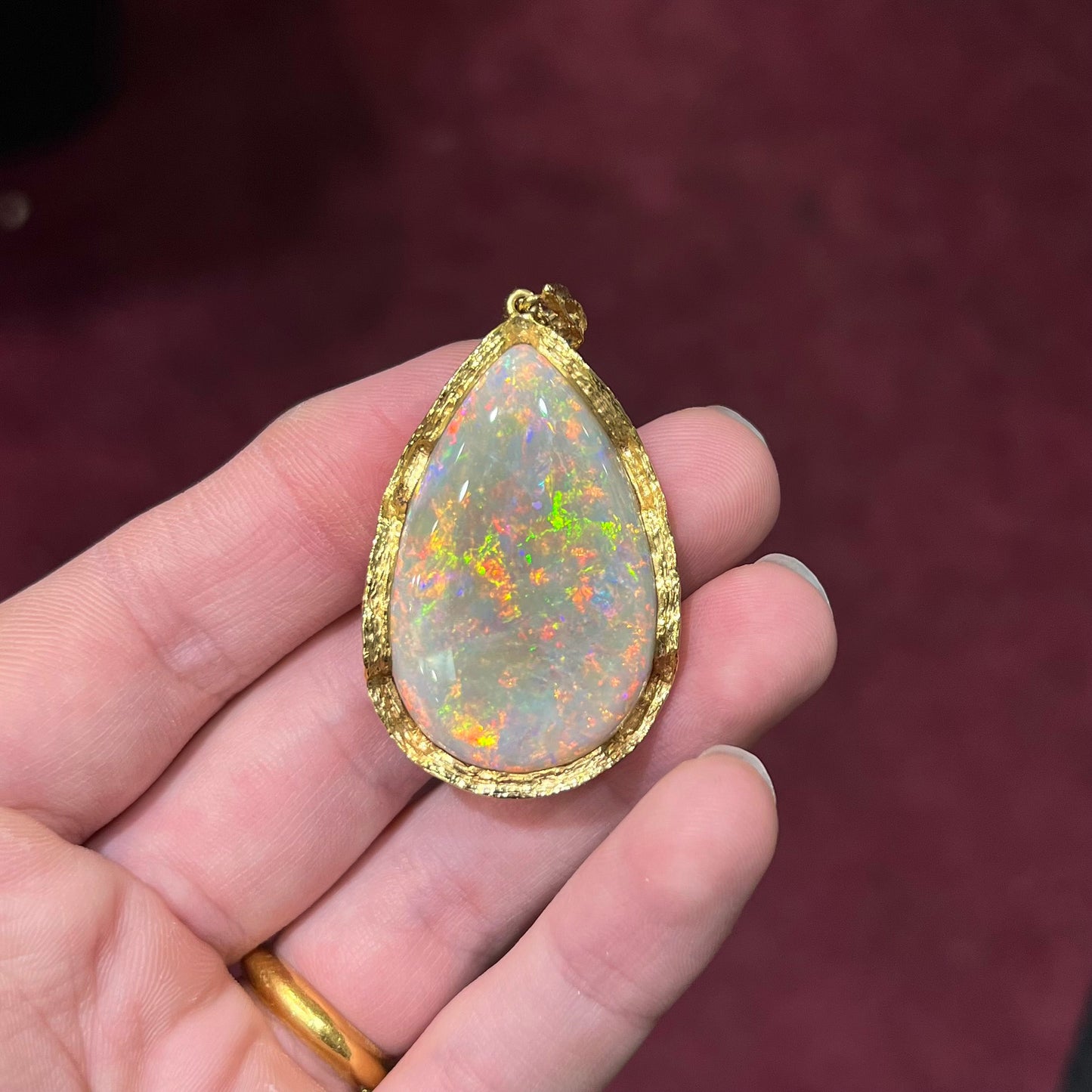 A ladies' natural, pear shaped, gray base Australian opal pendant set in 18 karat yellow gold.