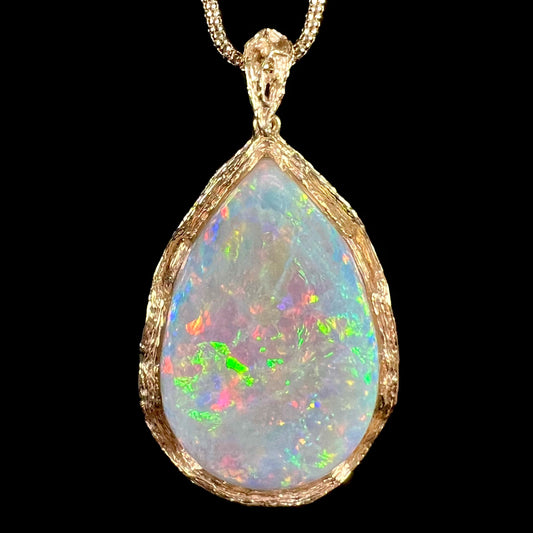A ladies' natural, pear shaped, gray base Australian opal pendant set in 18 karat yellow gold.