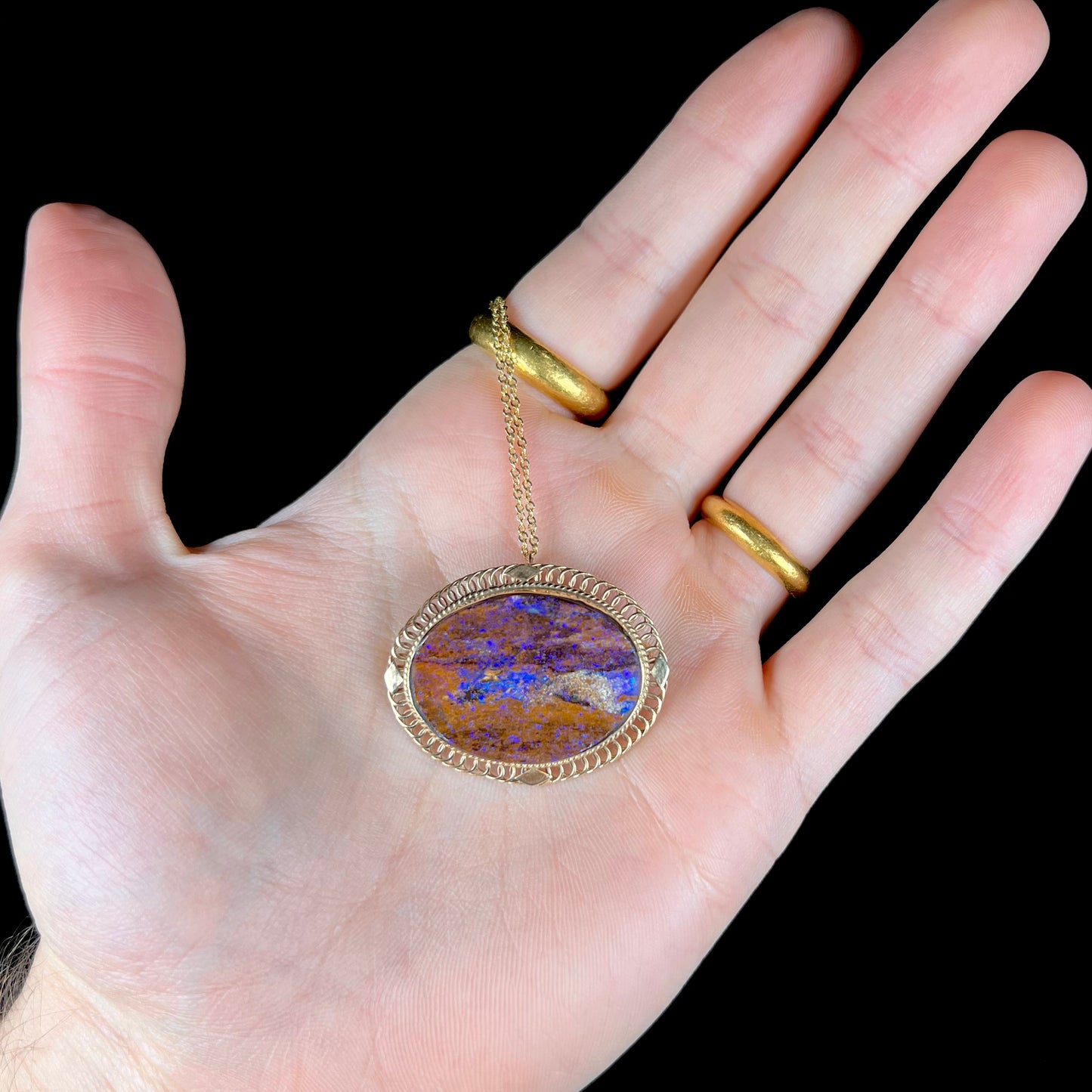 A yellow gold filigree style brooch/pendant combination piece set with a purple opalized wood stone from Duck Creek, Australia.