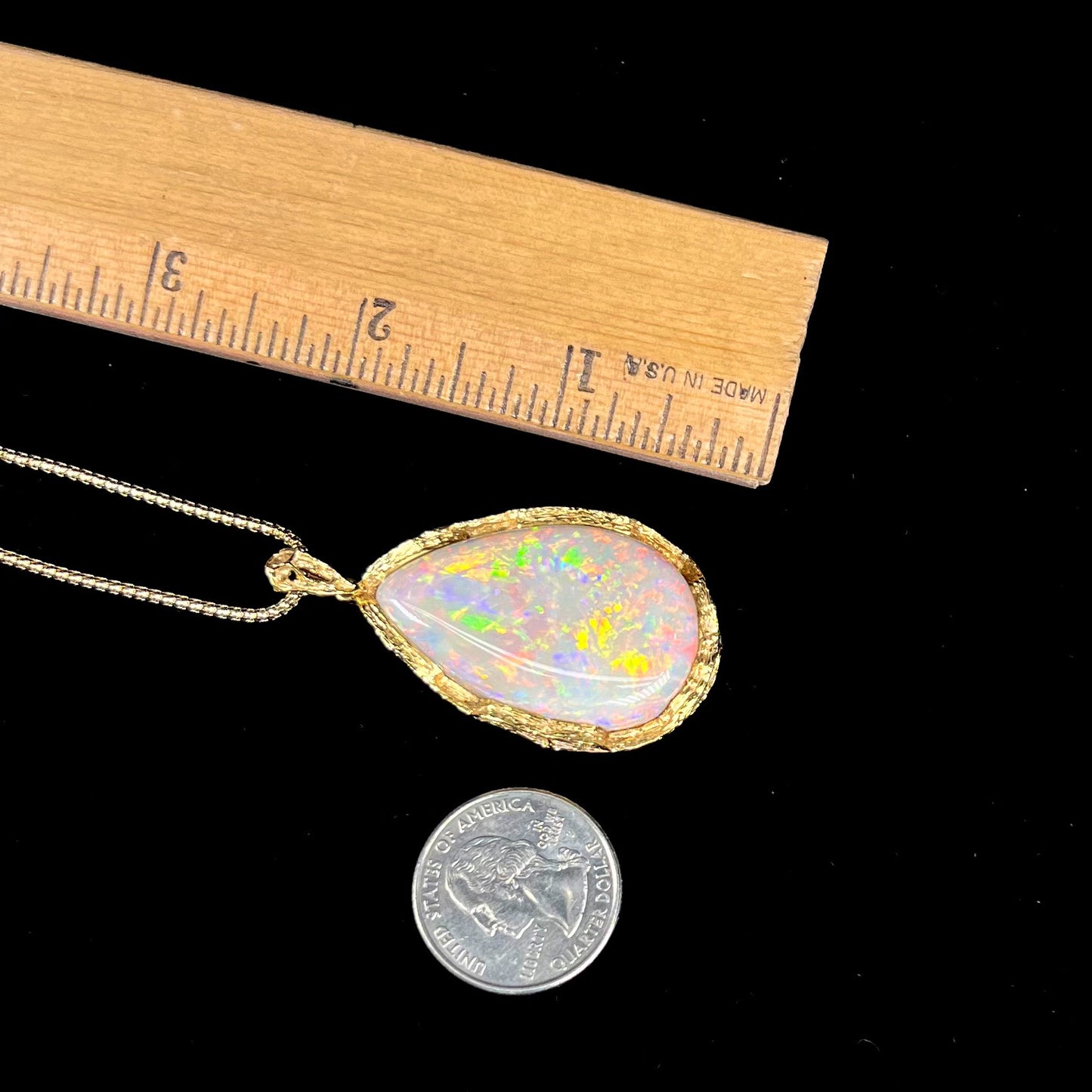 A ladies' natural, pear shaped, gray base Australian opal pendant set in 18 karat yellow gold.