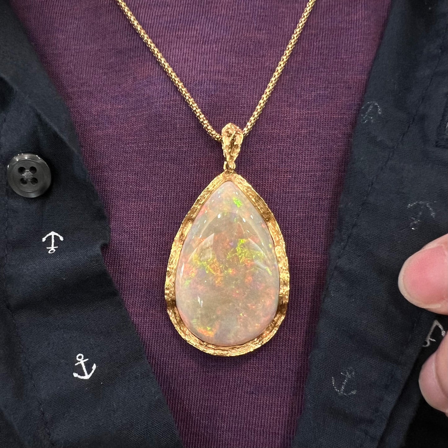A ladies' natural, pear shaped, gray base Australian opal pendant set in 18 karat yellow gold.