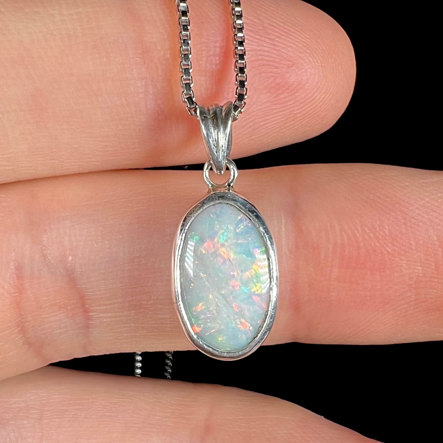A ladies' sterling silver necklace bezel set with a natural white crystal opal.  The opal has red and blue fire.