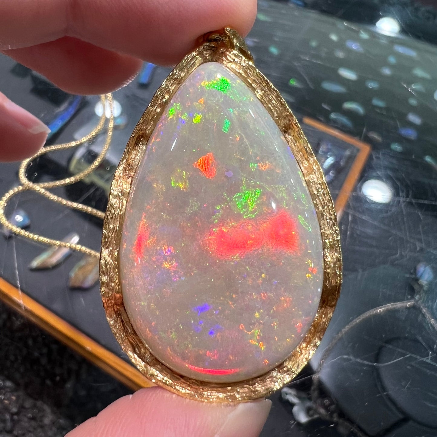 A ladies' natural, pear shaped, gray base Australian opal pendant set in 18 karat yellow gold.