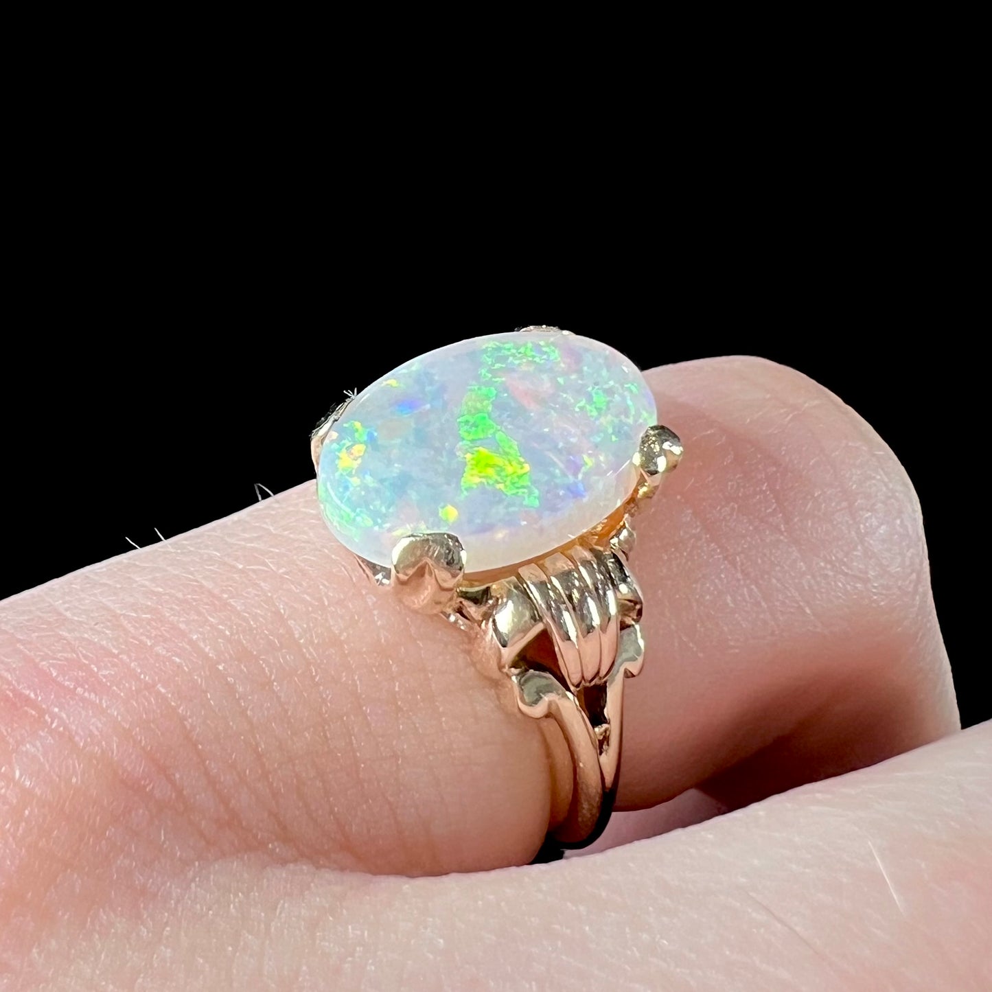 A ladies' Art Deco style natural opal solitaire ring in yellow gold. The opal is oval cut.