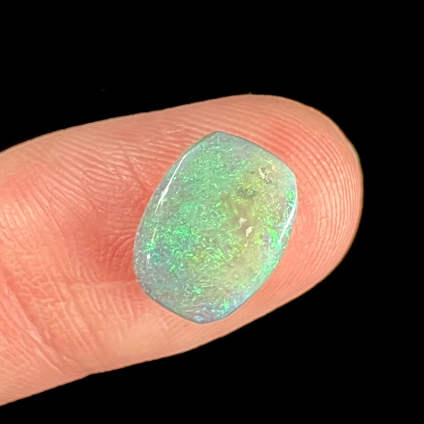 A 2.40ct barrel shaped Lightning Ridge semi-crystal opal. The stone has blue and green colors.