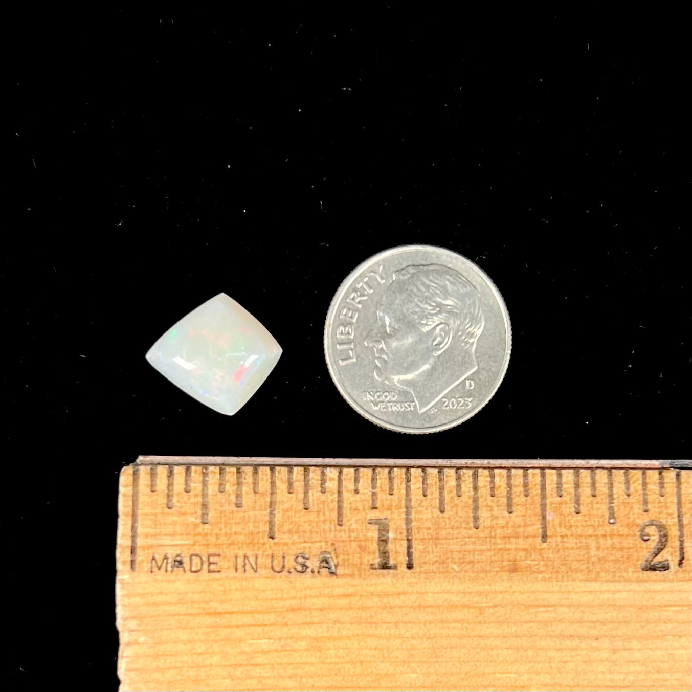 A loose, kite shaped white opal stone from Coober Pedy, Australia. The stone has subdued red colors.