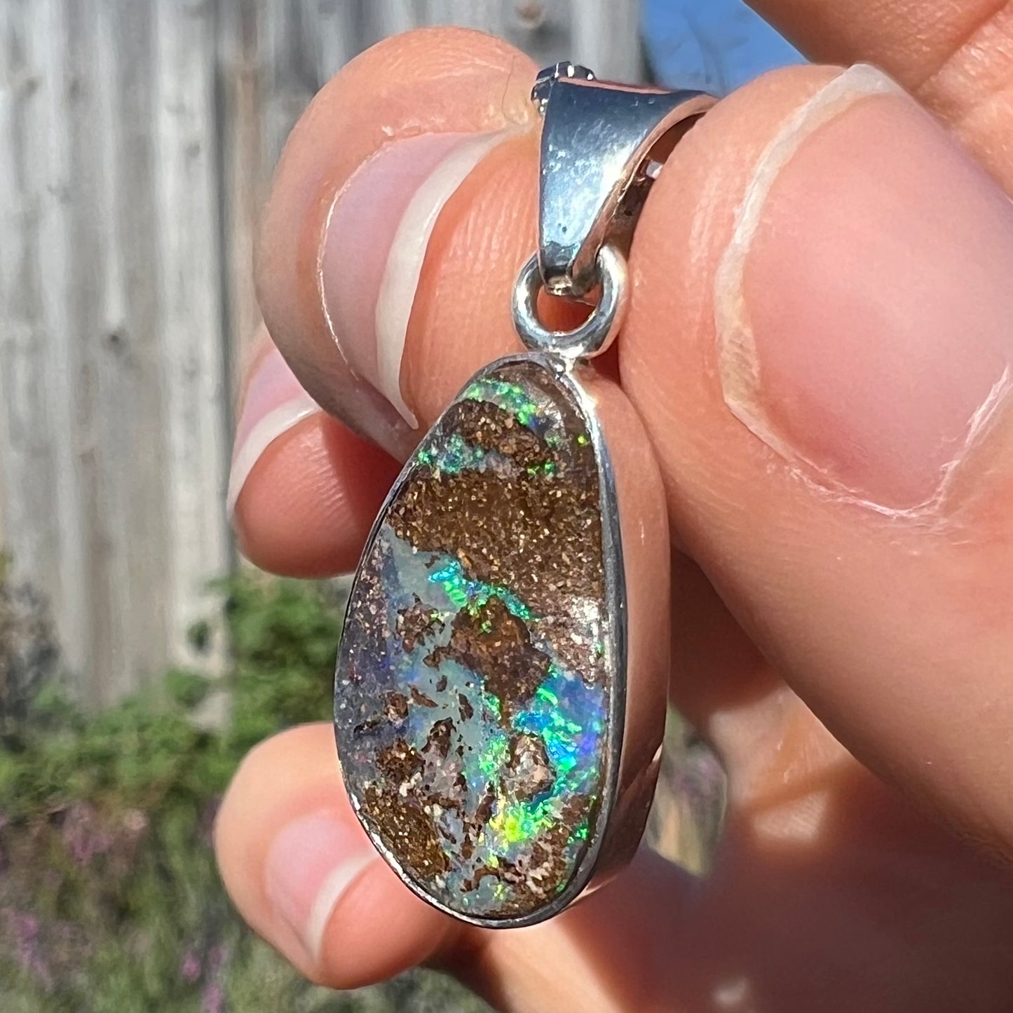 A sterling silver necklace set with a rainbow boulder opal stone.
