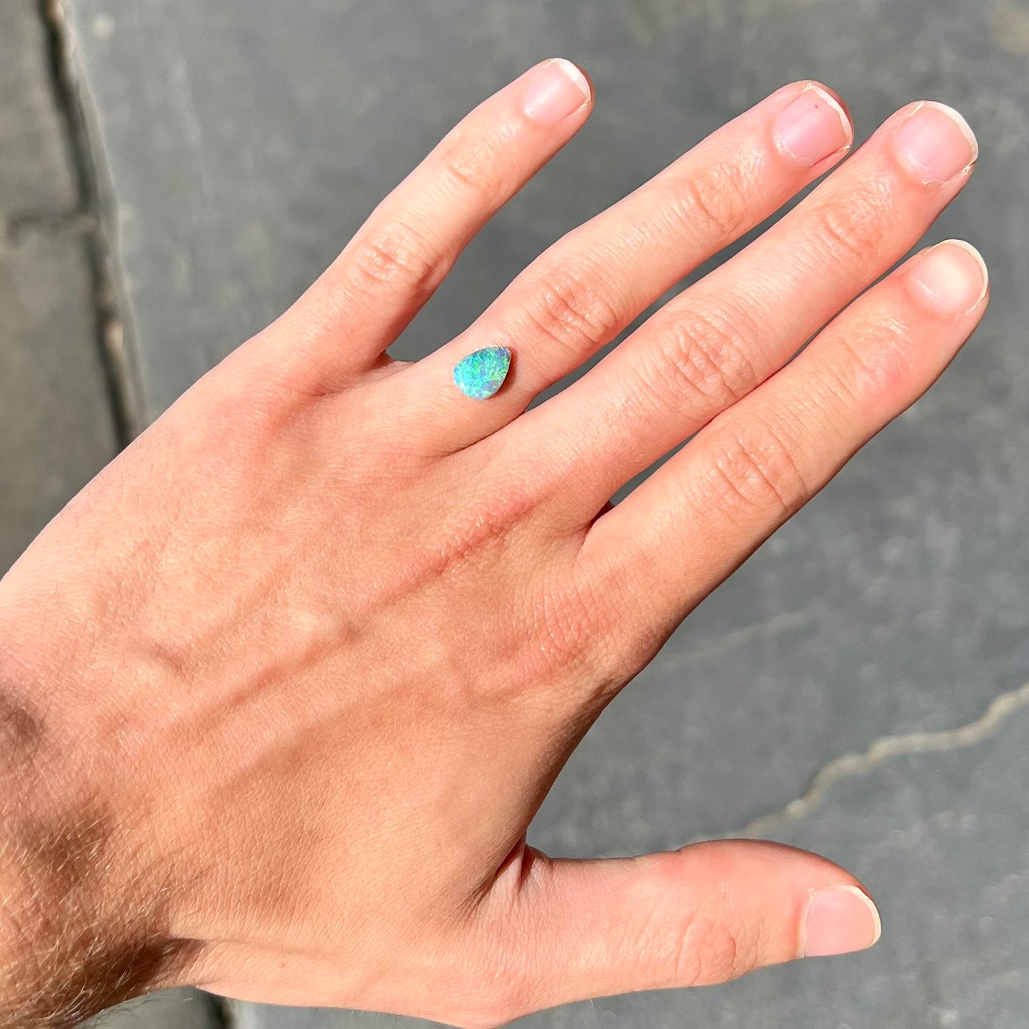 A loose, pear shaped black opal from LIghtning Ridge, Australia. The opal shines blue and green colors.